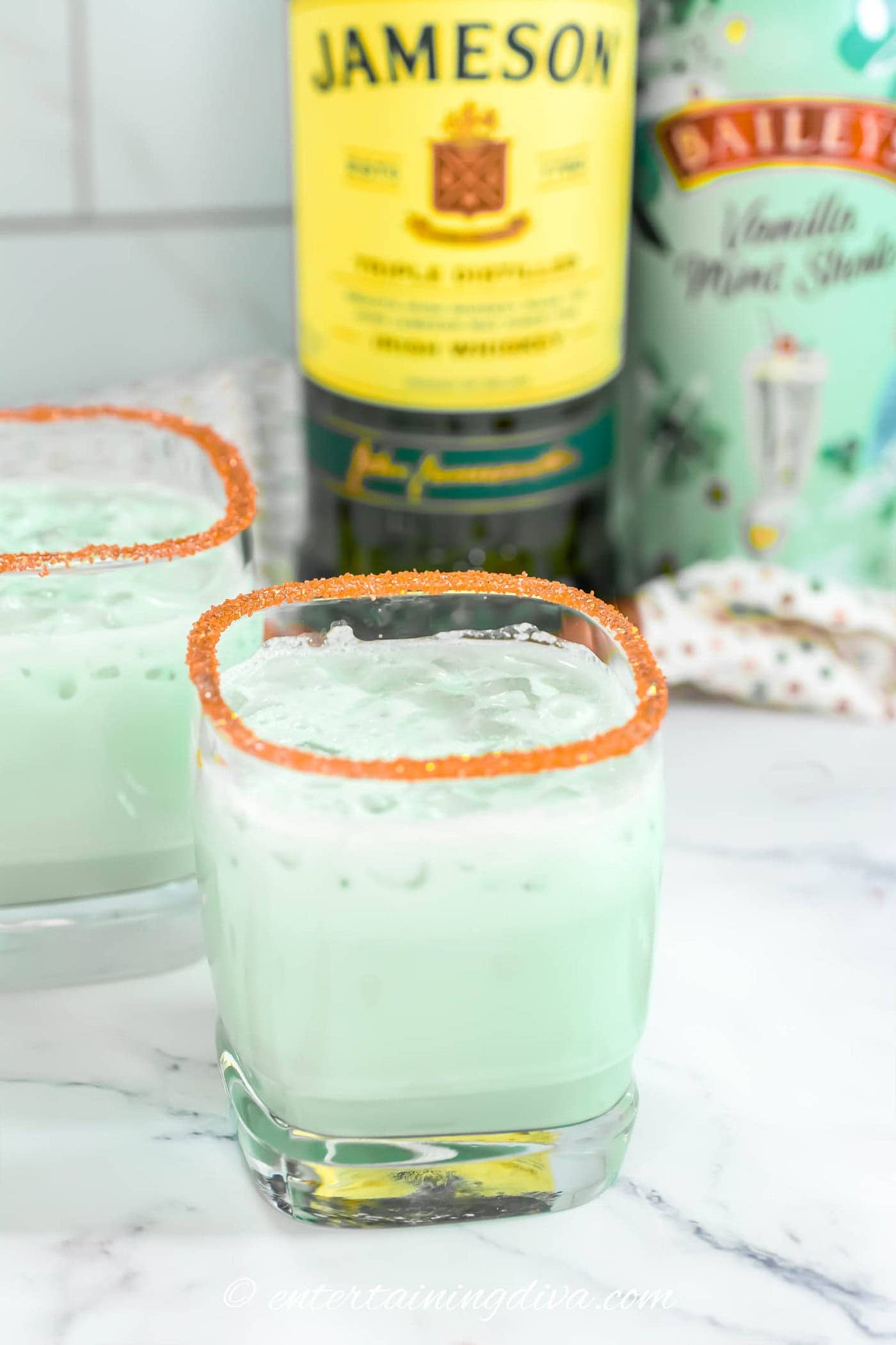 shamrock shake cocktail in front of a bottle of Jameson Irish whiskey and Bailey's vanilla mint shake