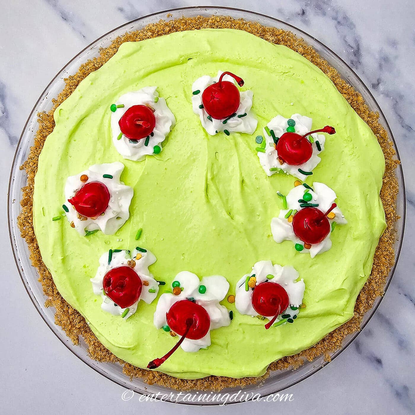 shamrock shake pie garnished with shipped cream, maraschino cherries and green sprinkles