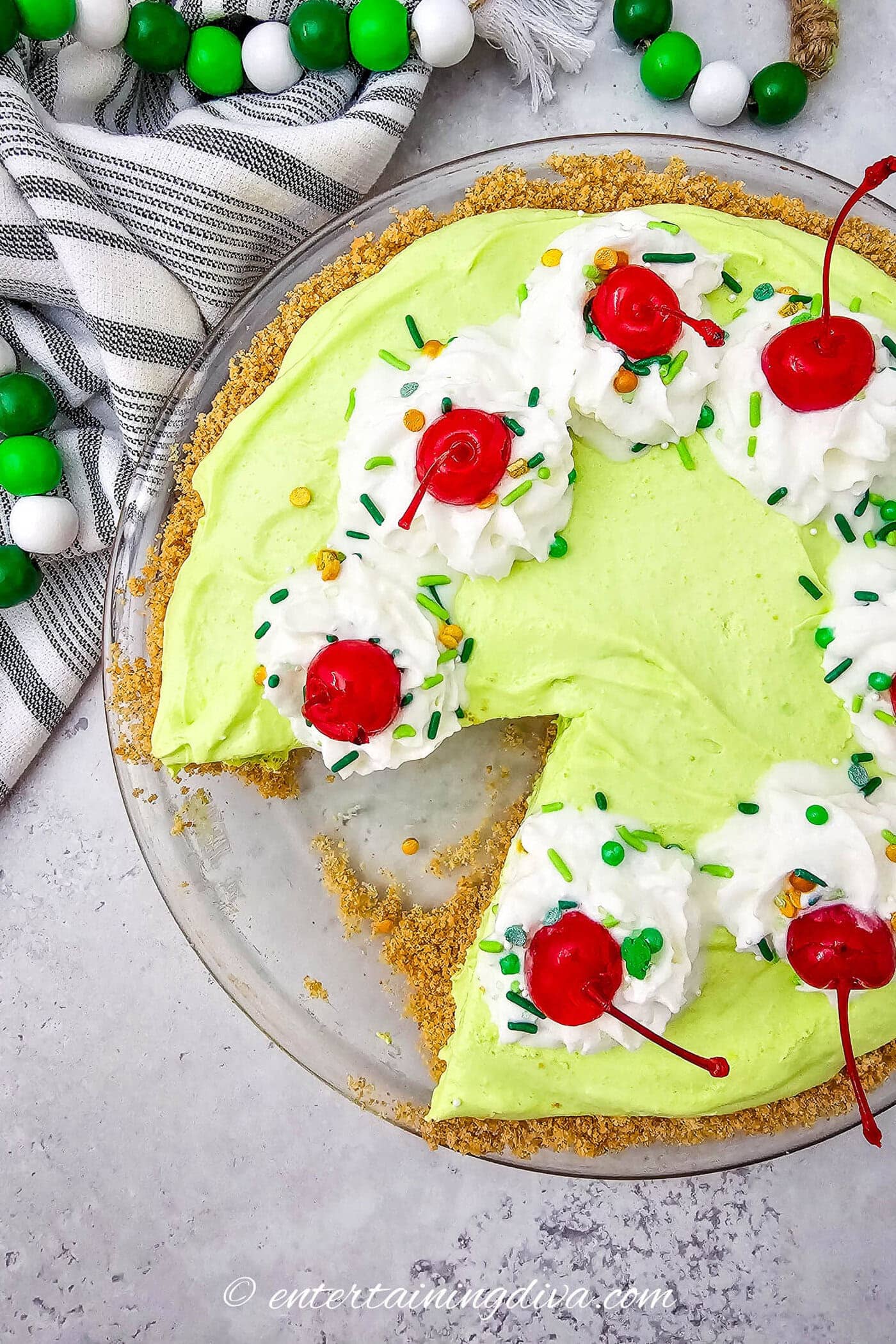 Overhead of shamrock shake pie garnished with whipped cream, maraschino cherries and green sprinkles.