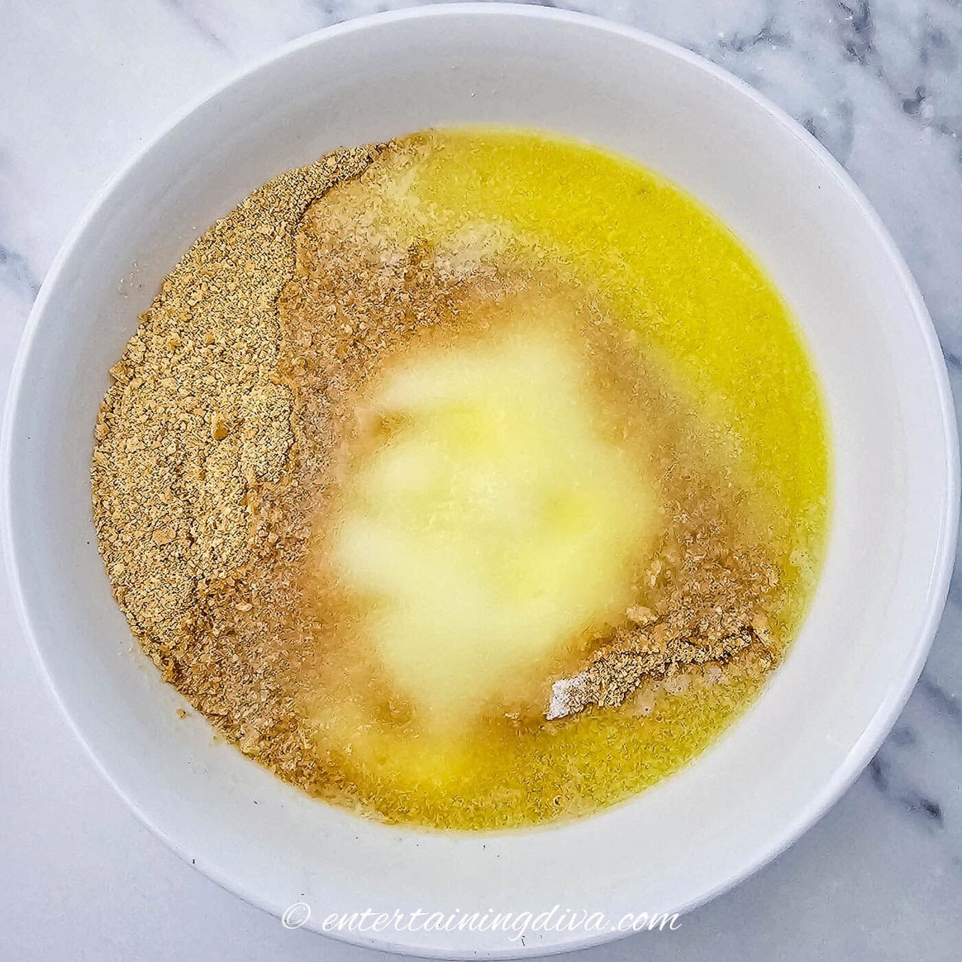 graham cracker crumbs mixed with butter and sugar in a mixing bowl