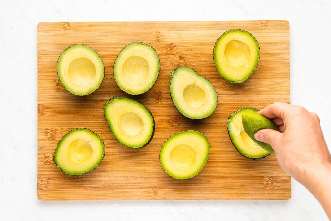 lime being juiced over avocado halves