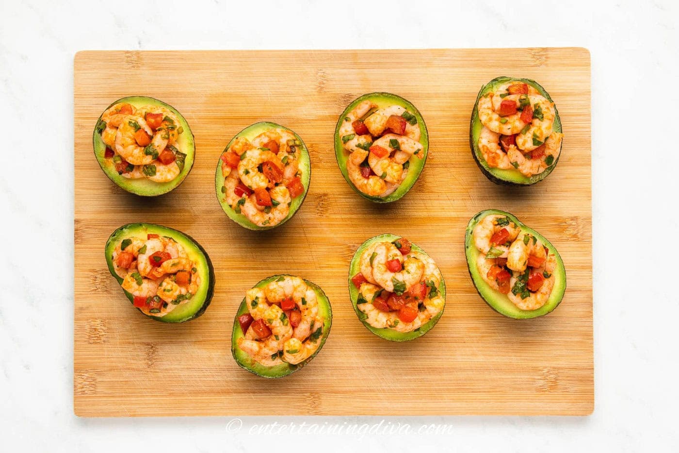 4 shrimp stuffed avocados on a cutting board