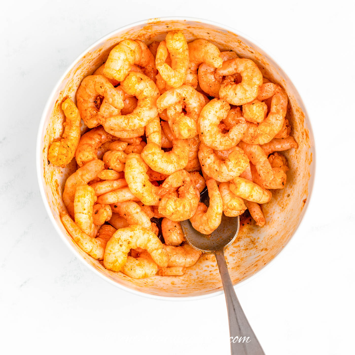 shrimp marinating in a bowl with a spoon