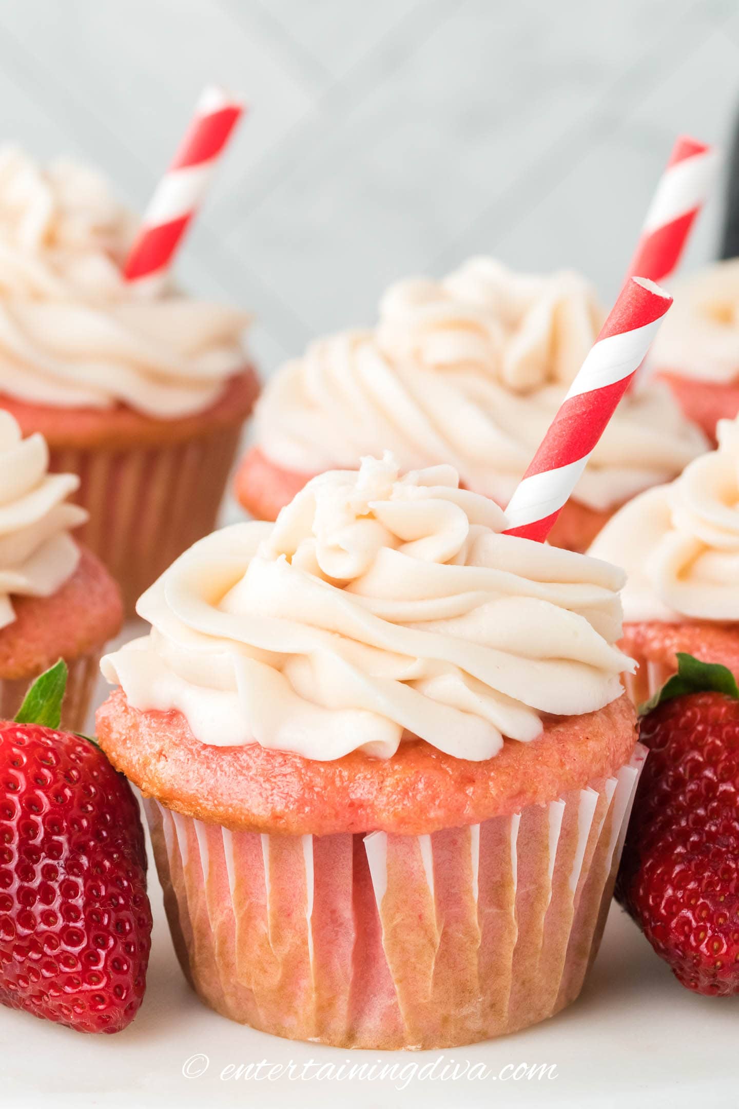 strawberry soda cupcakes with cream cheese frosting decorated with a red and white striped straw