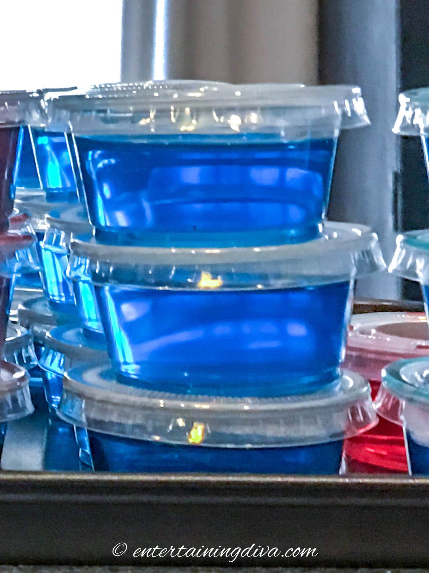 A close up of a stack of sour apple berry blue Jello shots