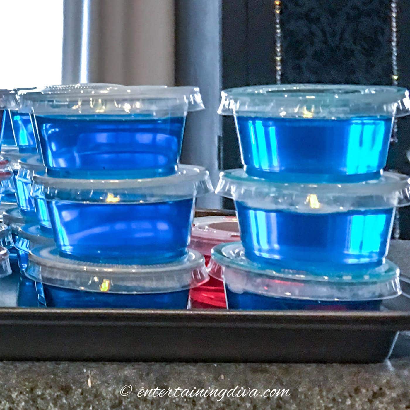 two stacks of sour apple blue jello shots on a tray