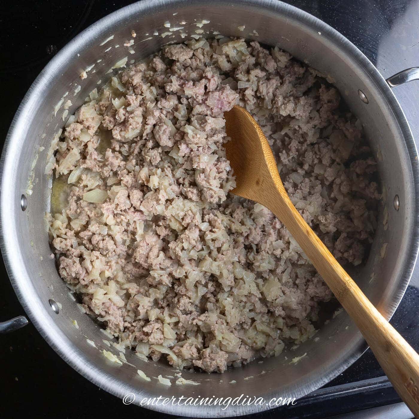 ground beef and onions being stirred in a stock pot