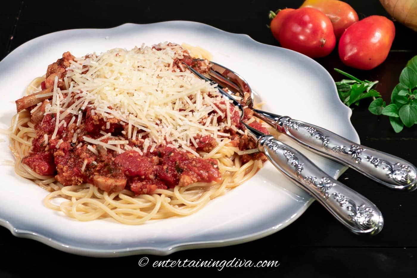 pasta meat sauce served with spaghetti and parmesan cheese on a plate