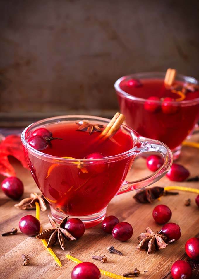 Two cups of cranberry mulled wine on a wooden table.