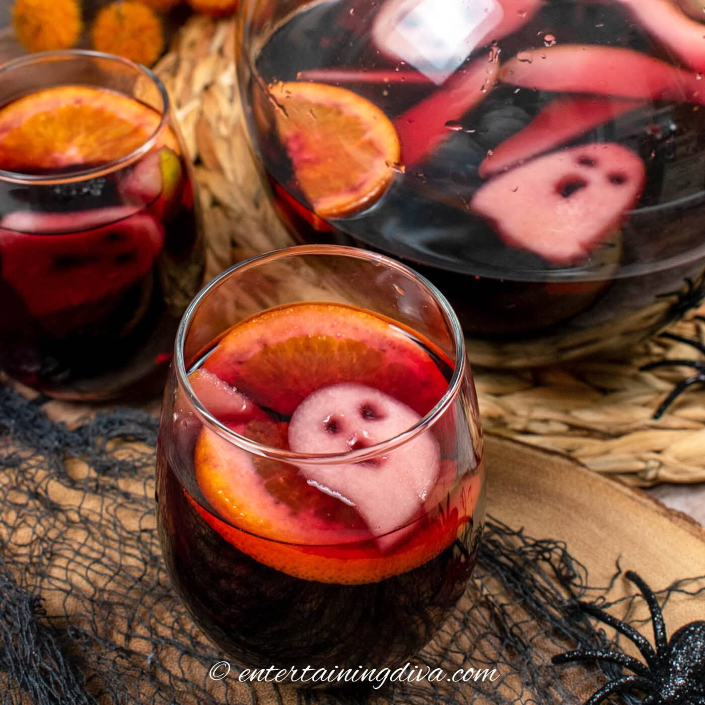 Two glasses of spooky Halloween sangria with a pitcher in the background