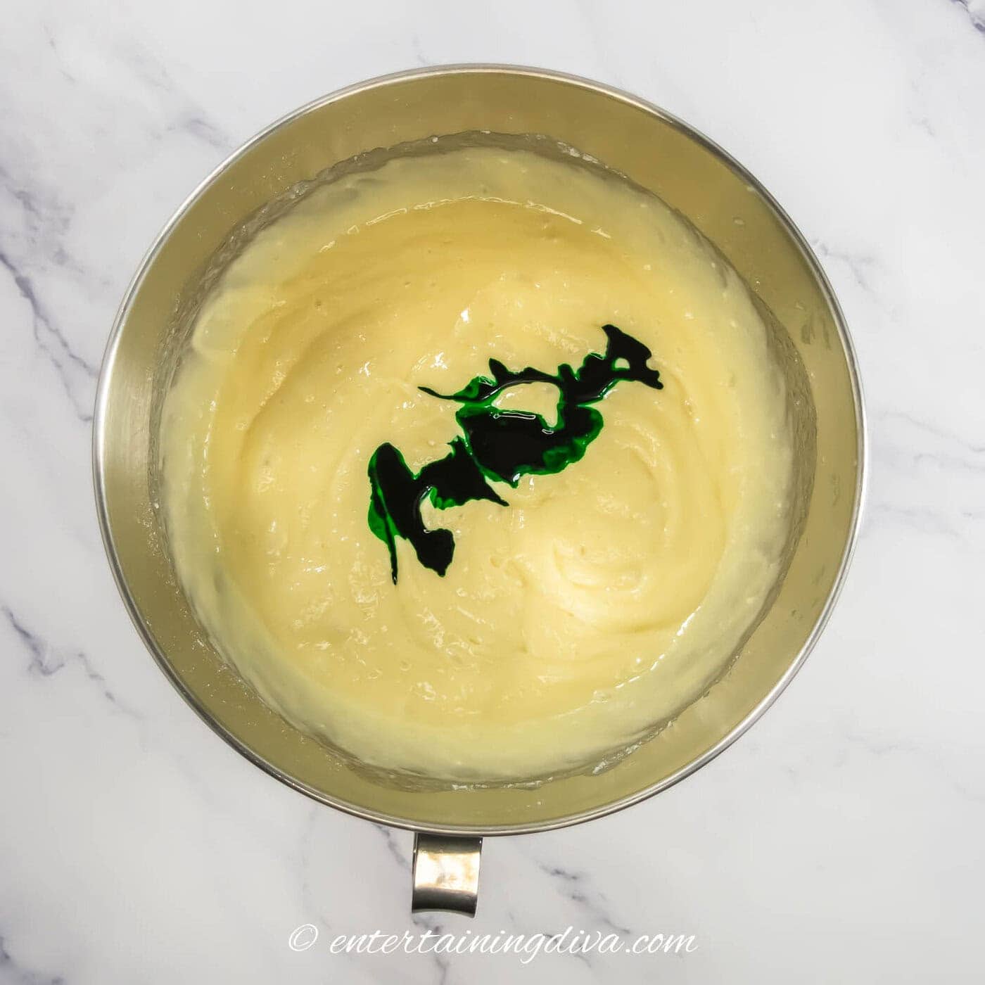 cake batter in a bowl with green food coloring before it has been mixed