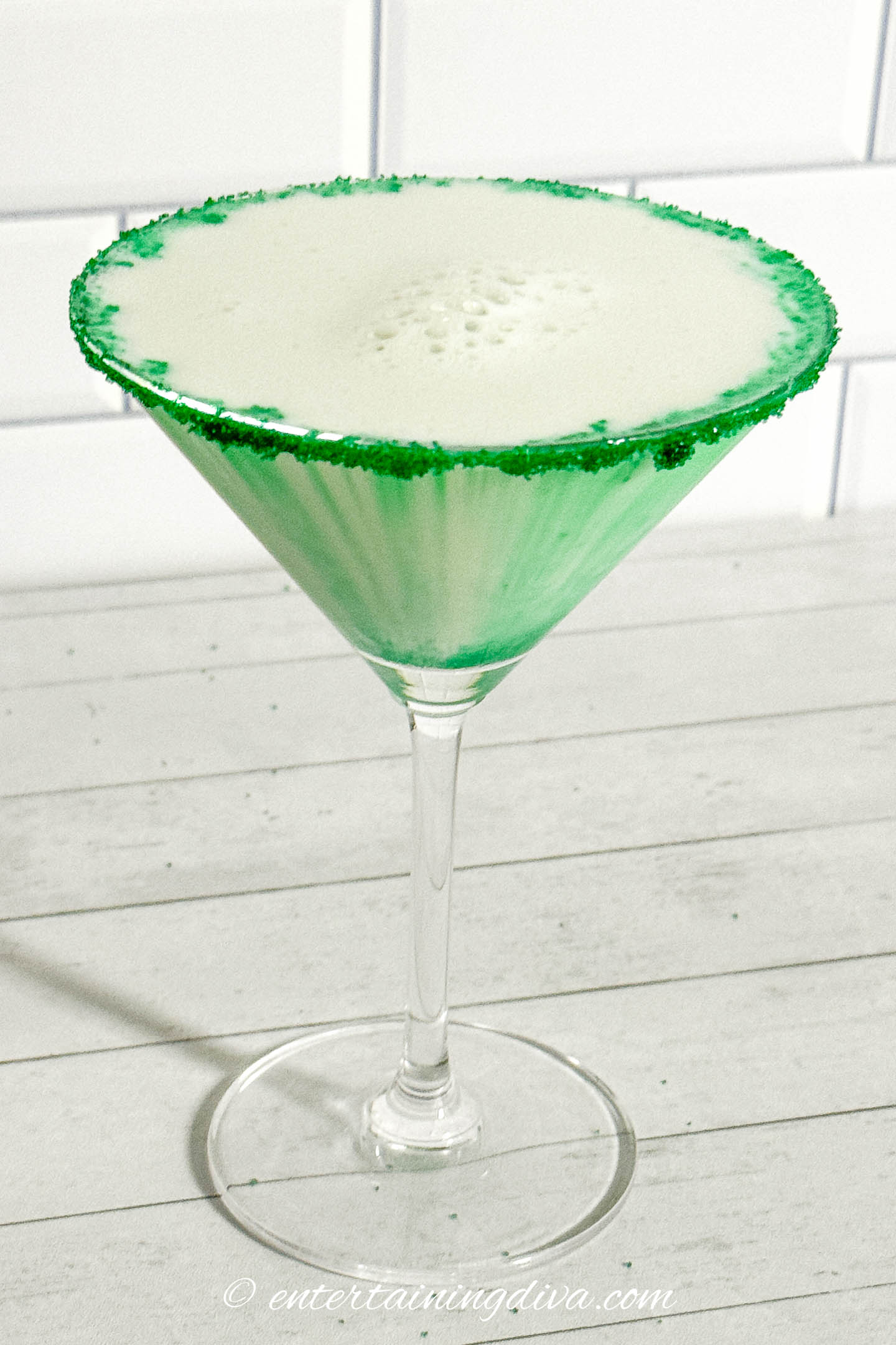 A martini glass rimmed with green sugar and filled with a green St Patrick's Day martini