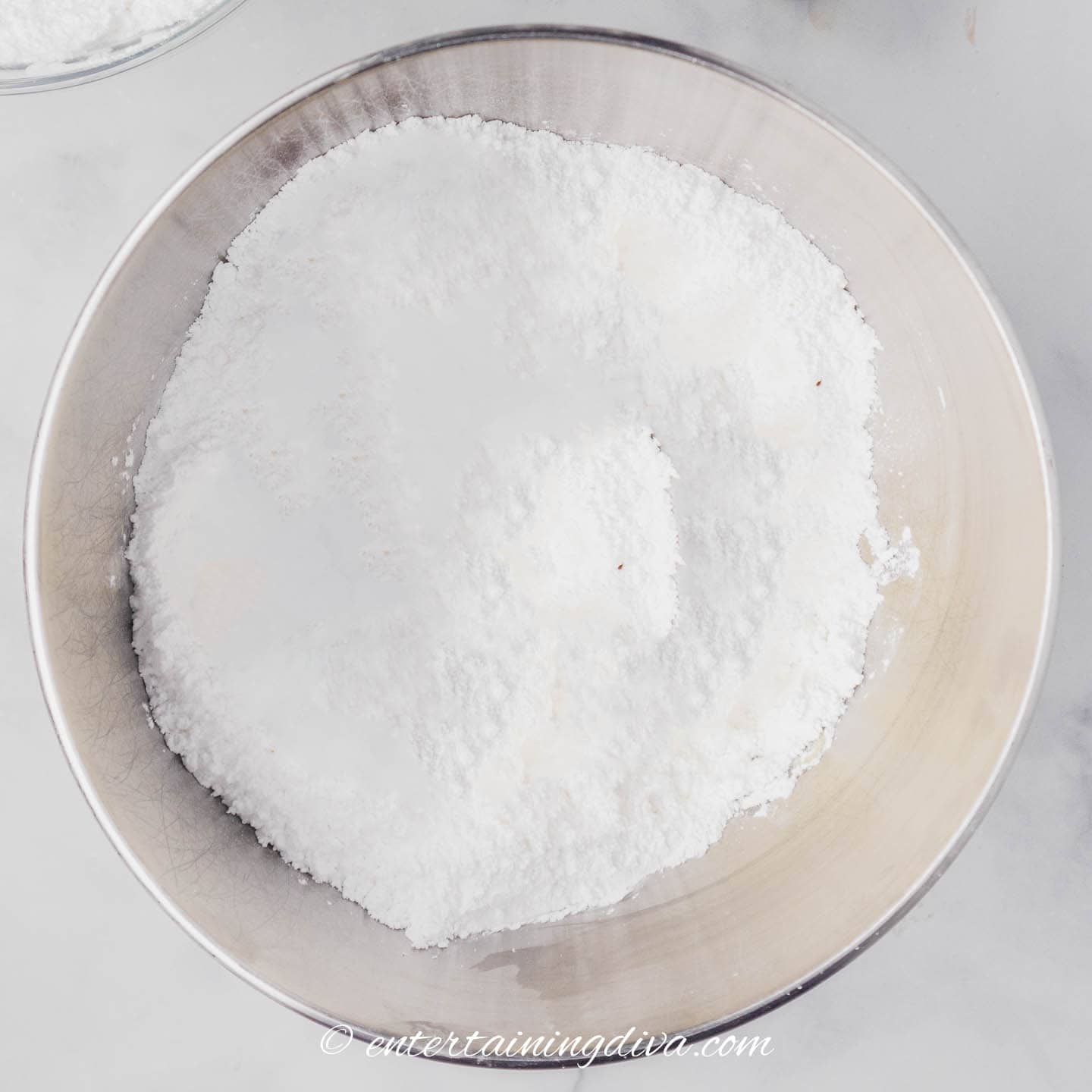 powdered sugar in a mixing bowl on top of creamed butter and cream cheese
