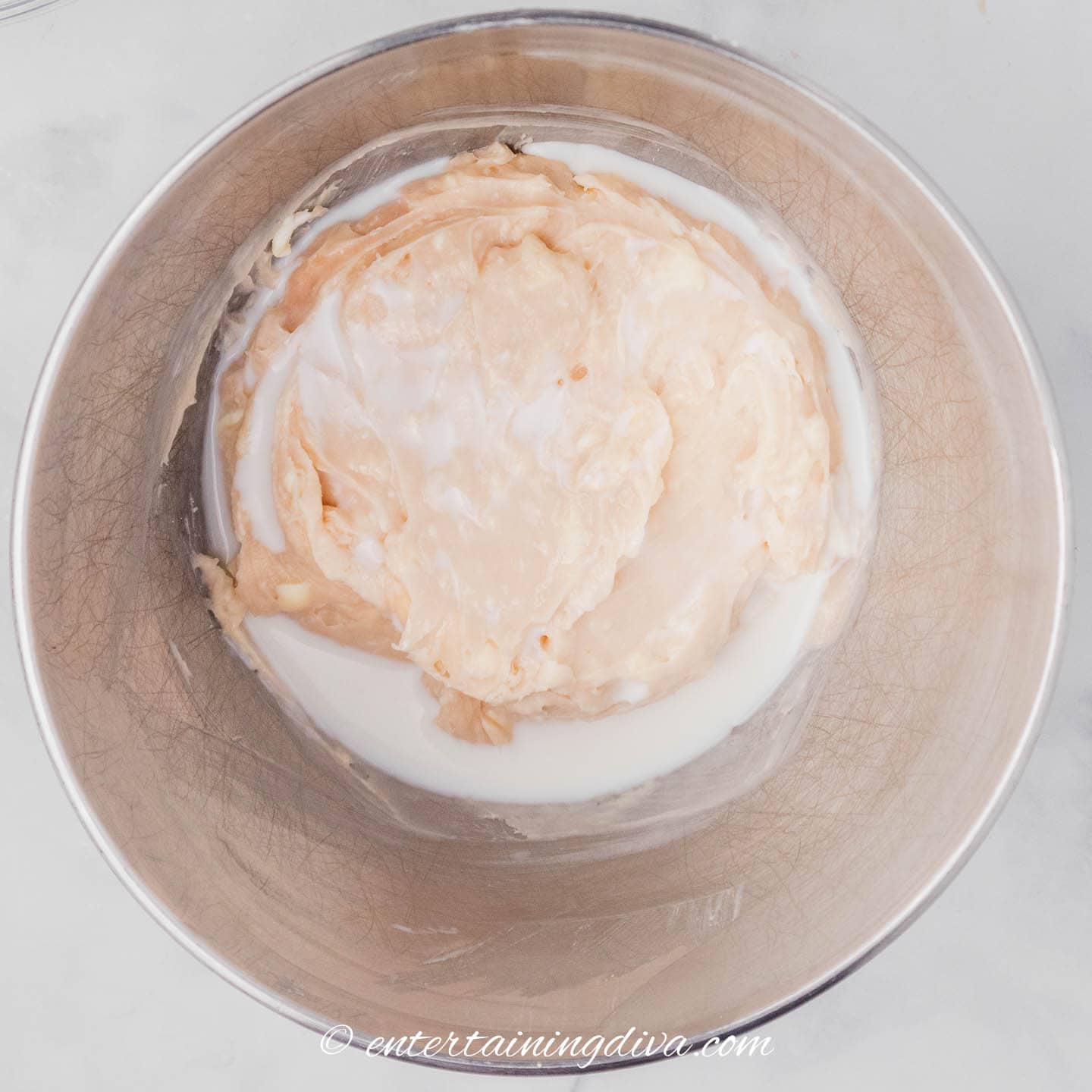 strawberry cream cheese frosting with milk in a mixing bowl