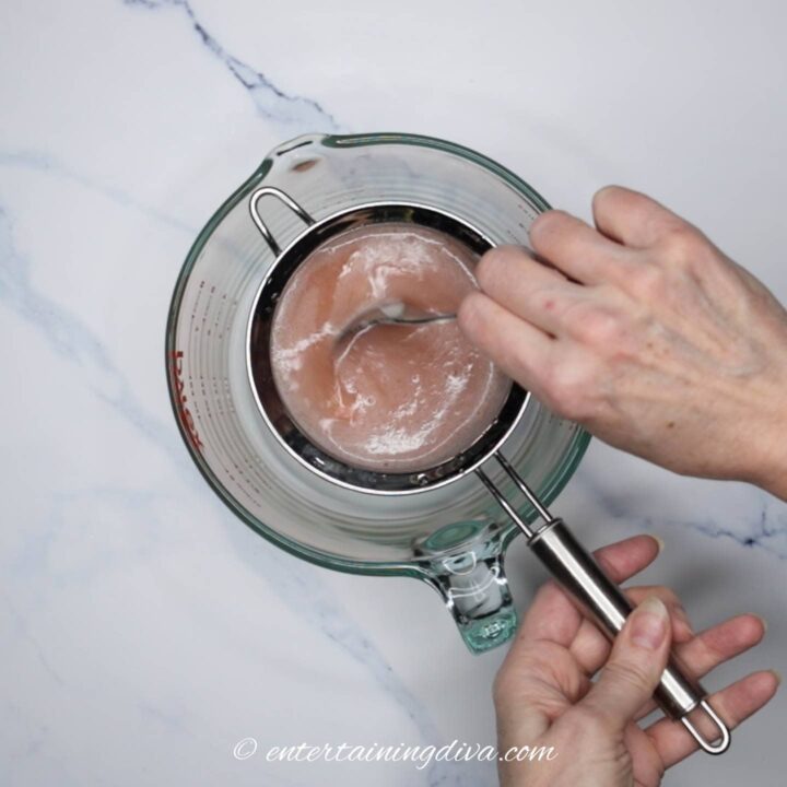 Strawberry mixture being strained into a bowl