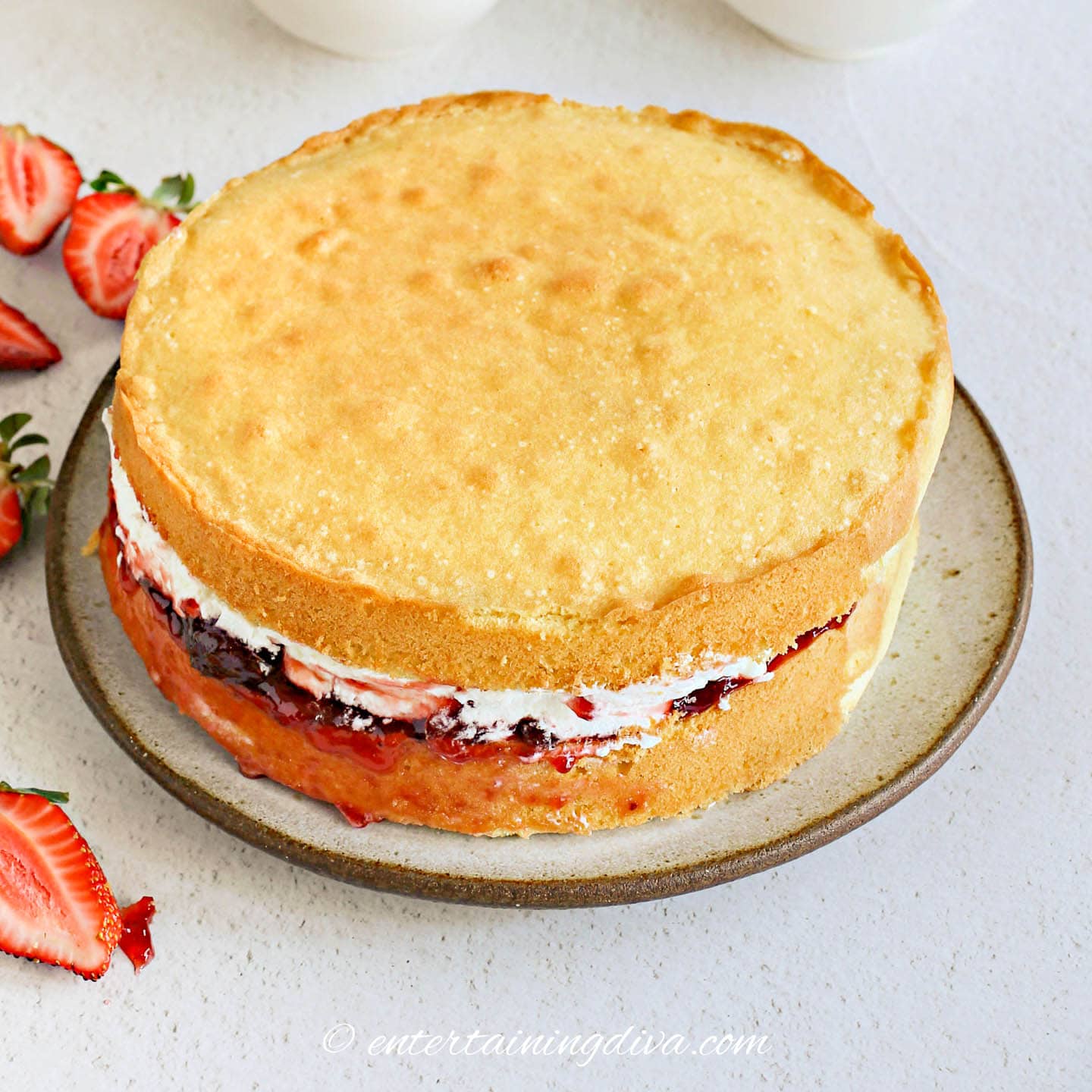 second cake layer on top of whipped cream, strawberries, jam and bottom layer