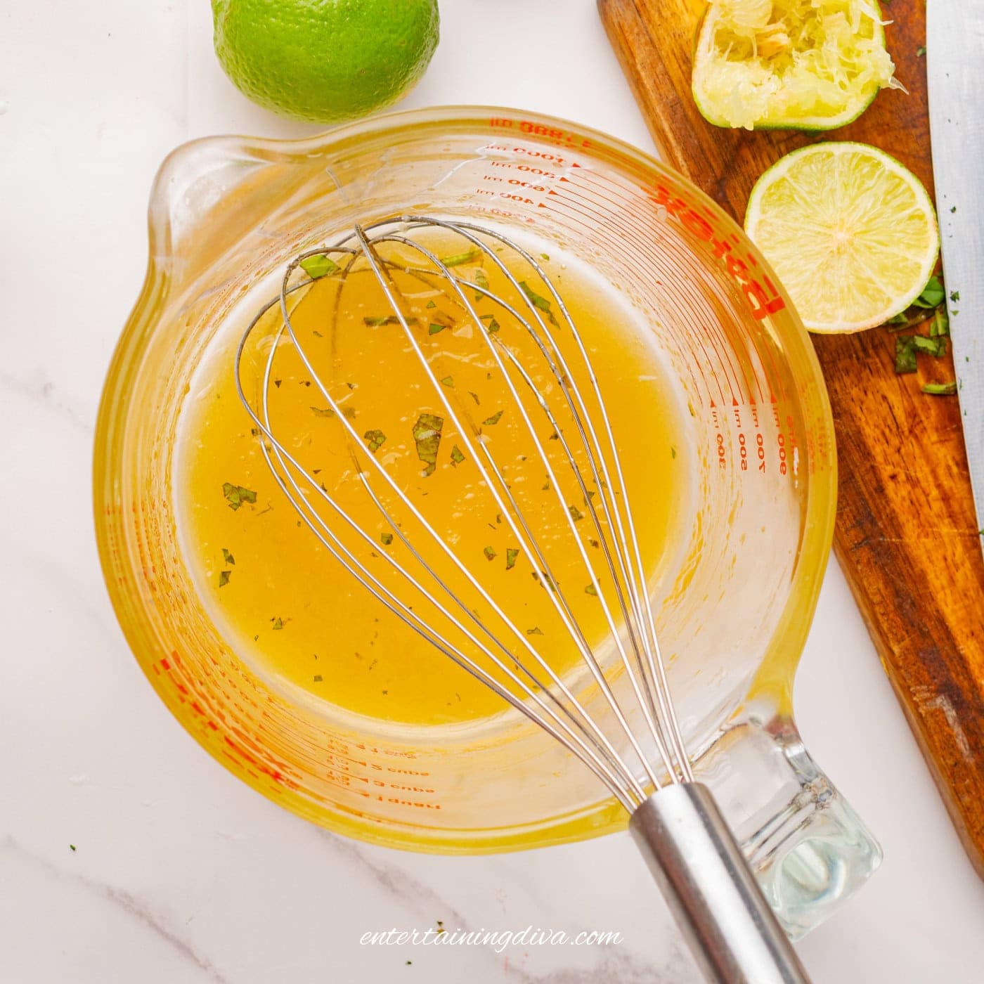 honey lime salad dressing in a mixing bowl with a whisk