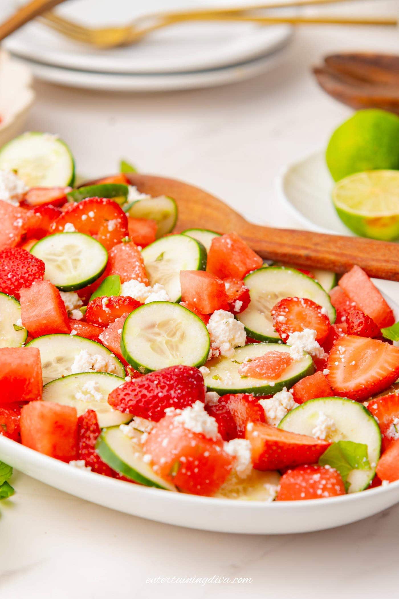 Strawberry watermelon cucumber salad on a serving plate with a large spoon