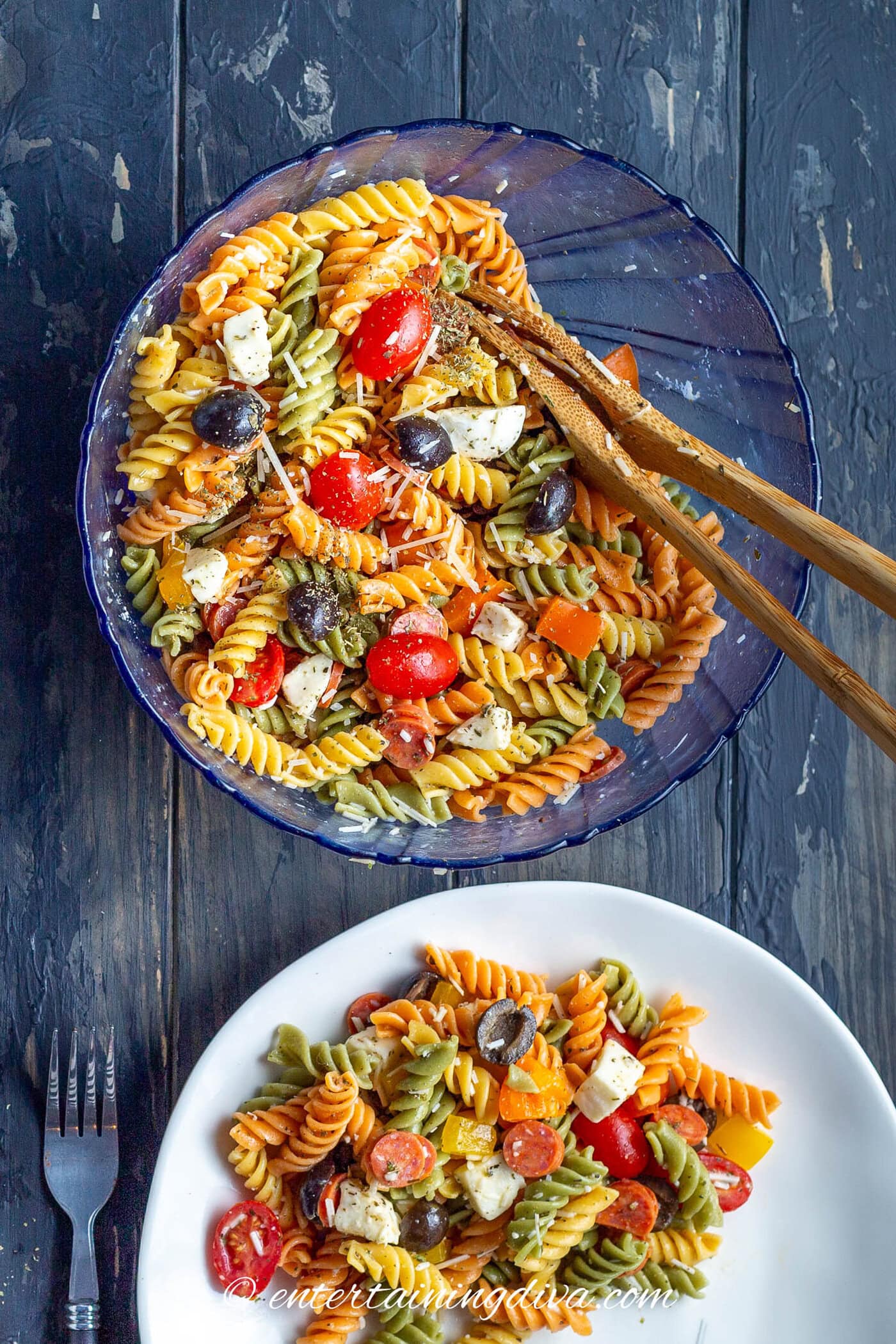 Close up of Italian pasta salad in a bowl with serving spoons