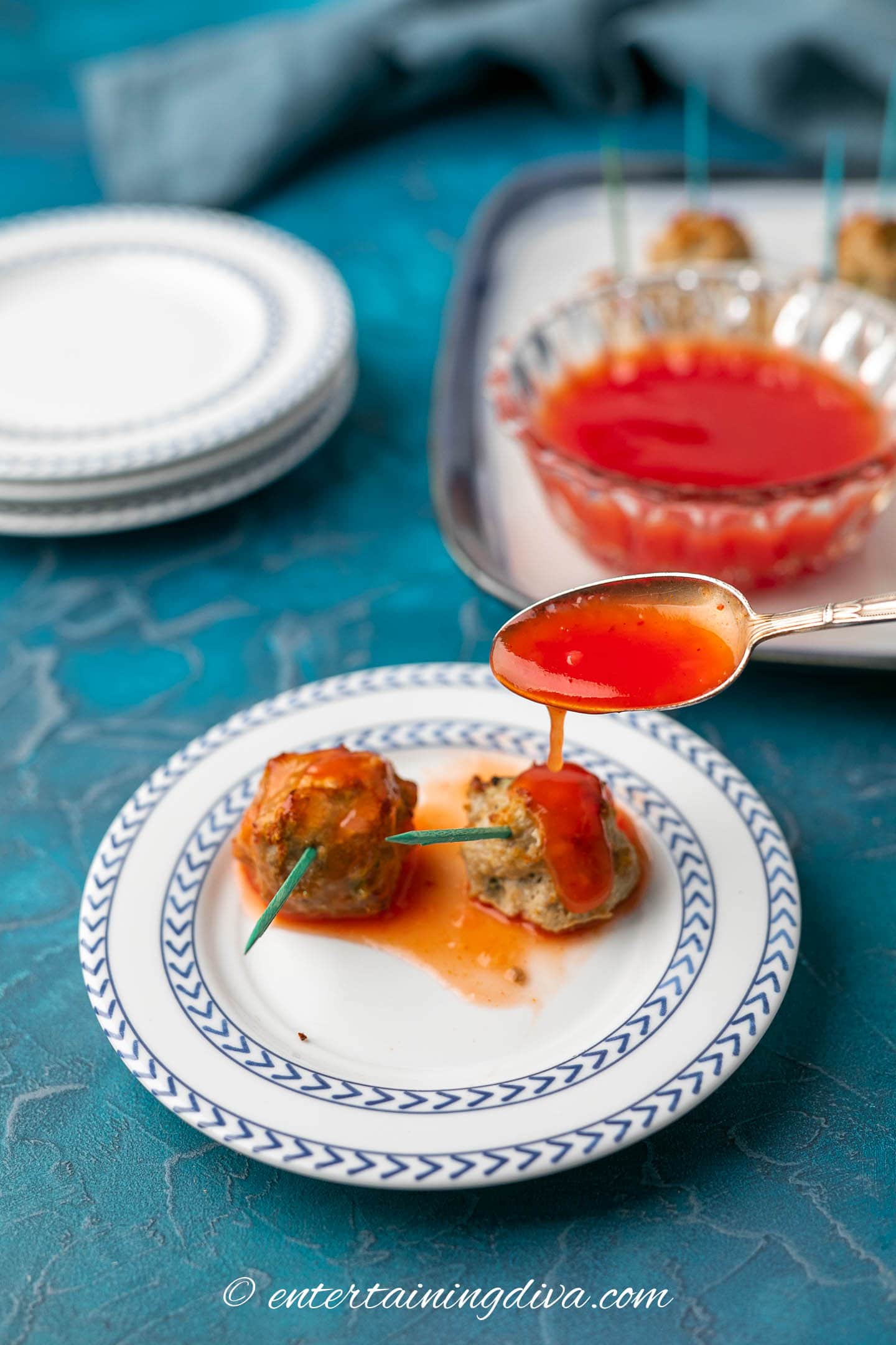 Meatballs on a plate with sweet and sour sauce being drizzled over them