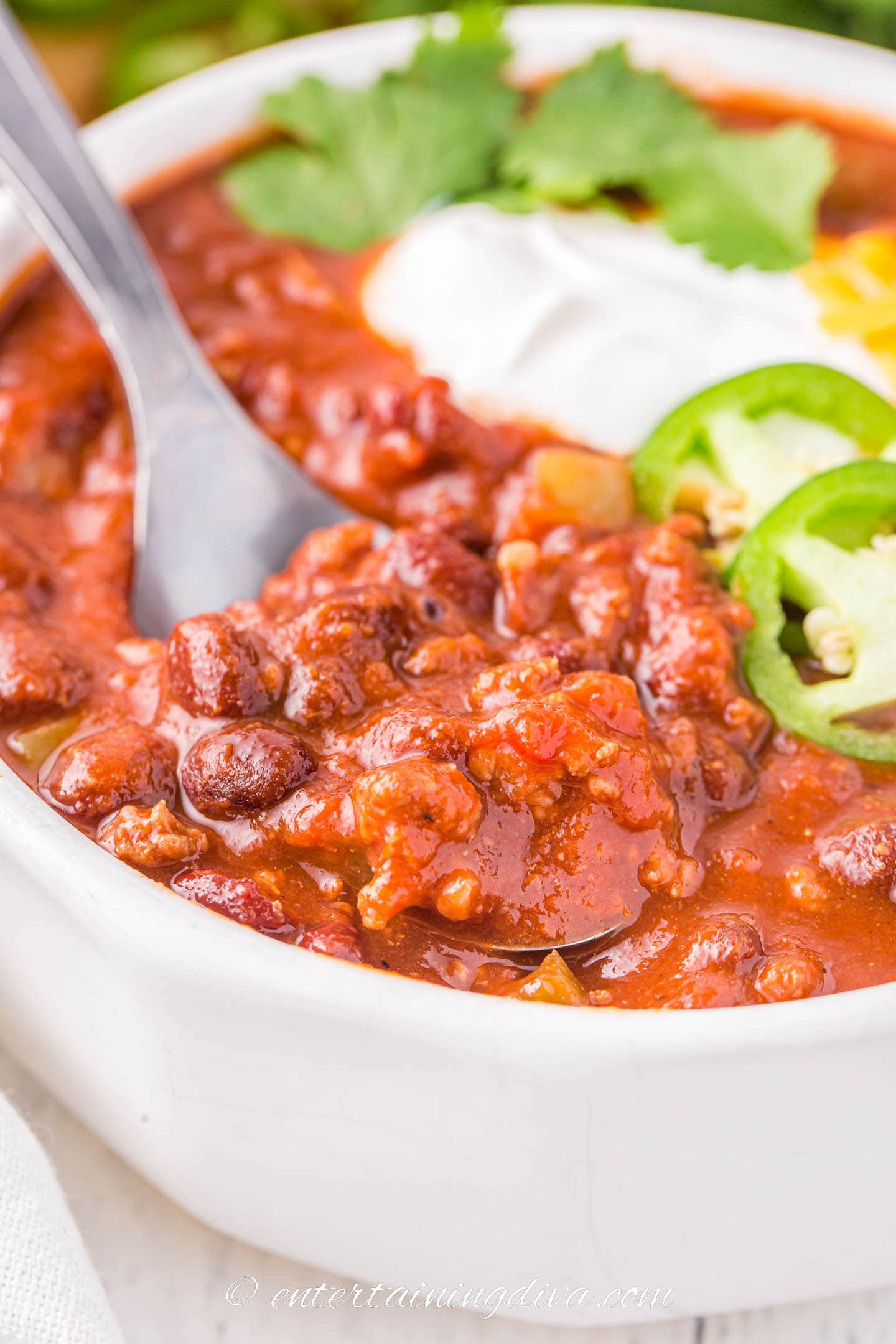 A spoon in a bowl of thick chili