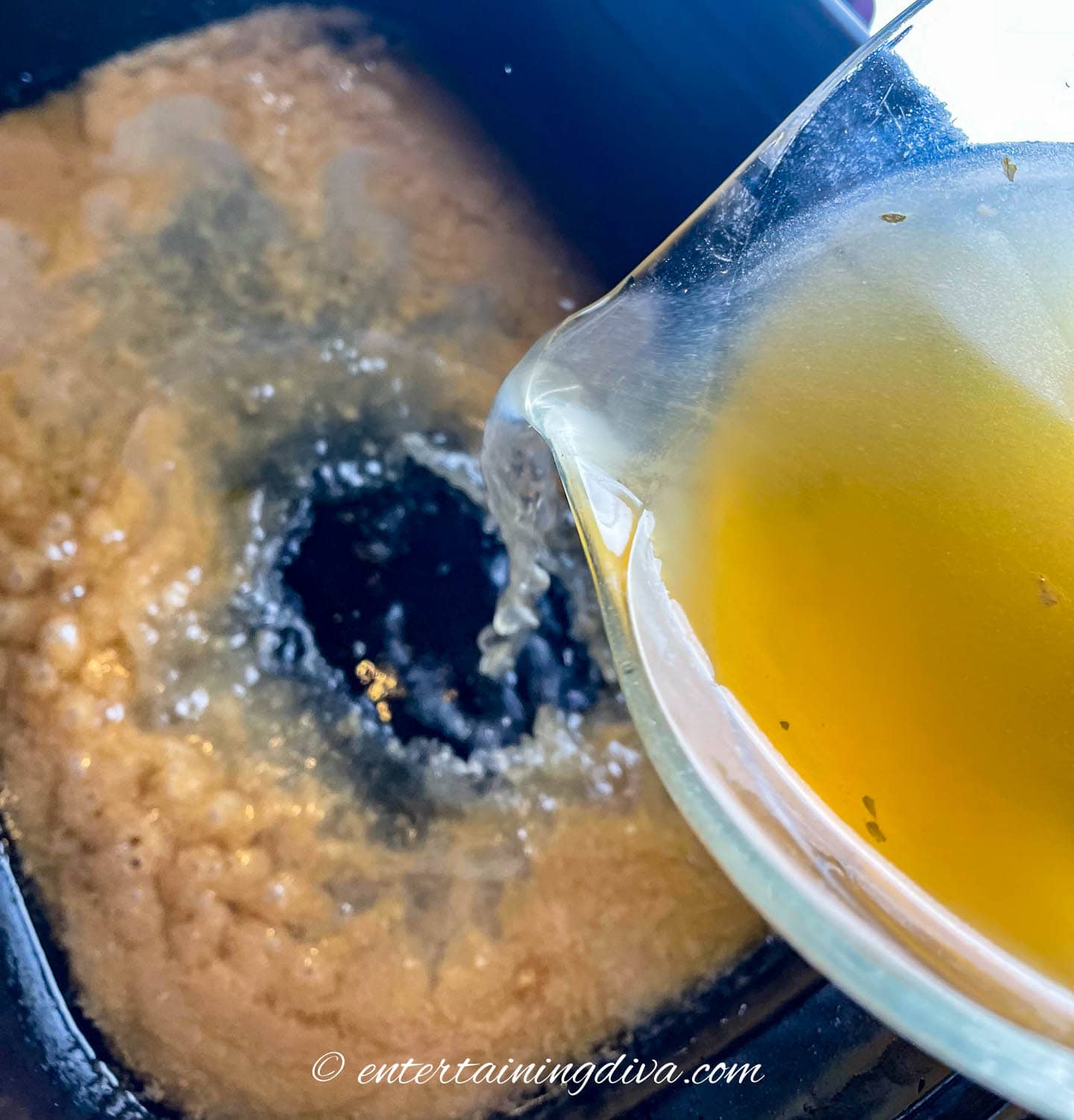 chicken stock being added to turkey drippings in a roasting pan