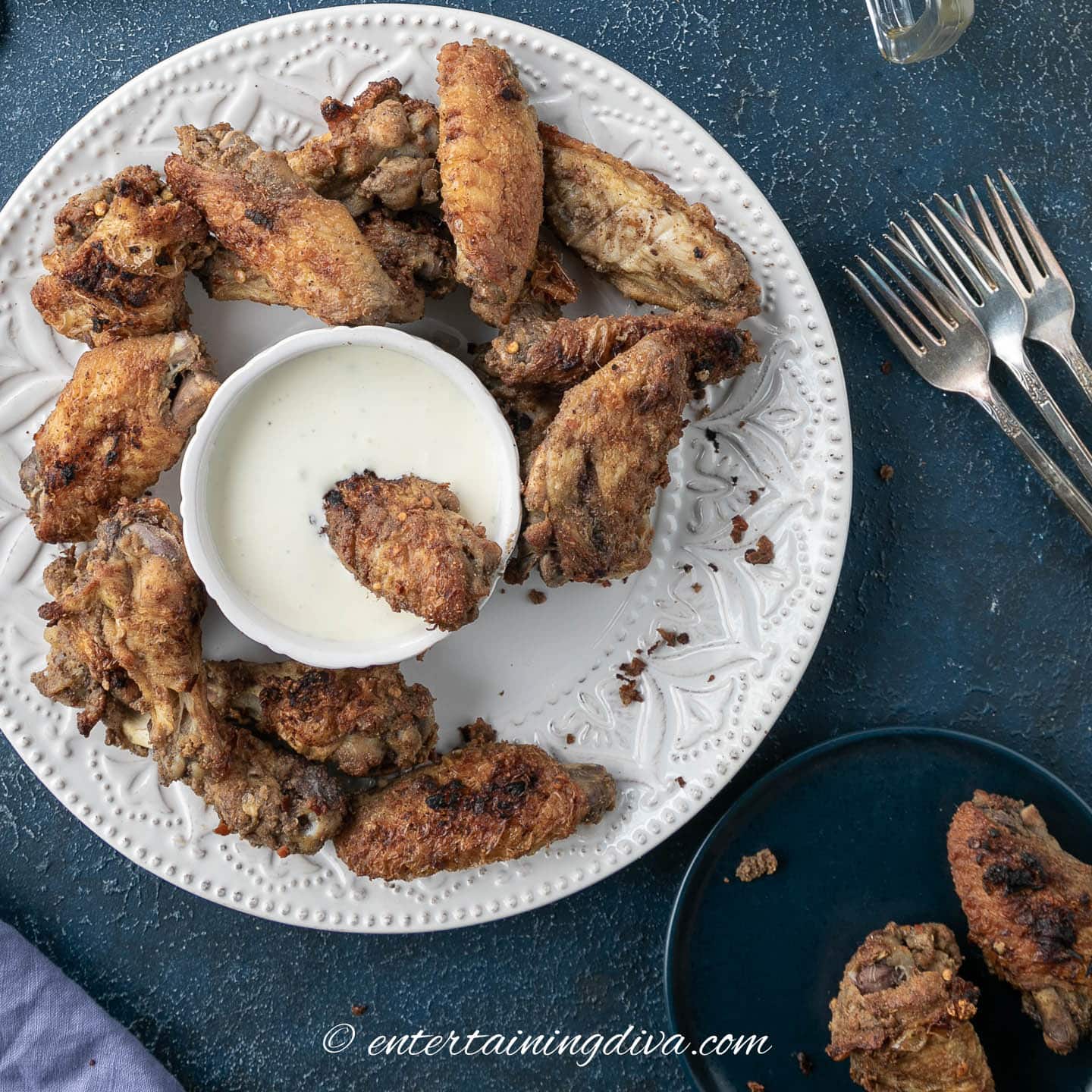 marinated Asian spice chicken wing being dipped in a bowl of blue cheese dressing surrounded by more wings