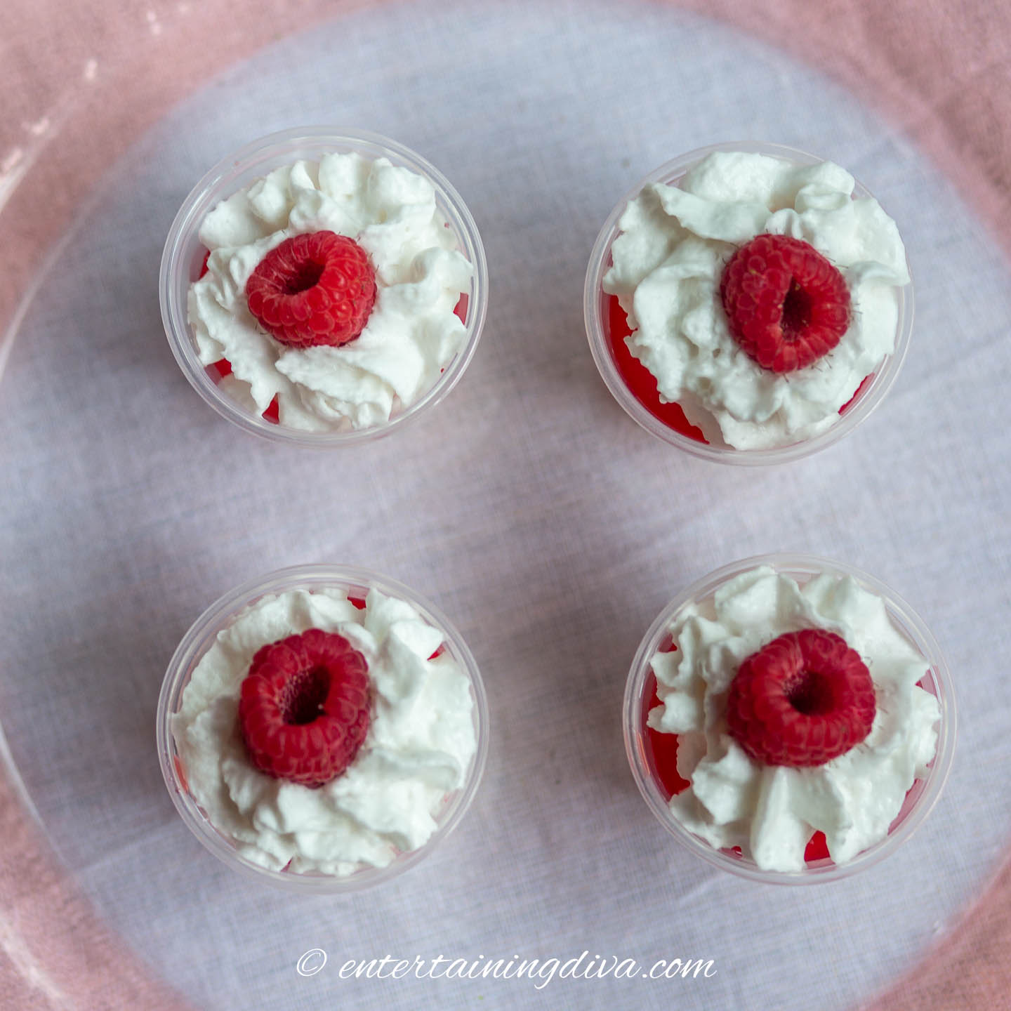 Jello shots with whipped cream and a raspberry on top