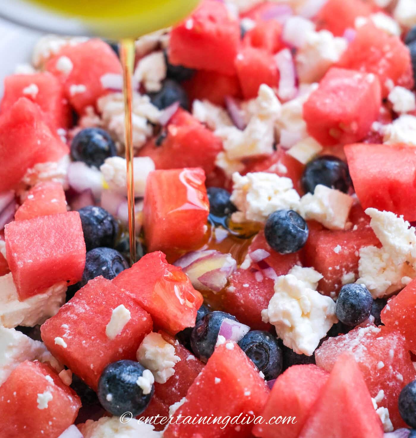 lemon dressing being poured onto a watermelon feta salad