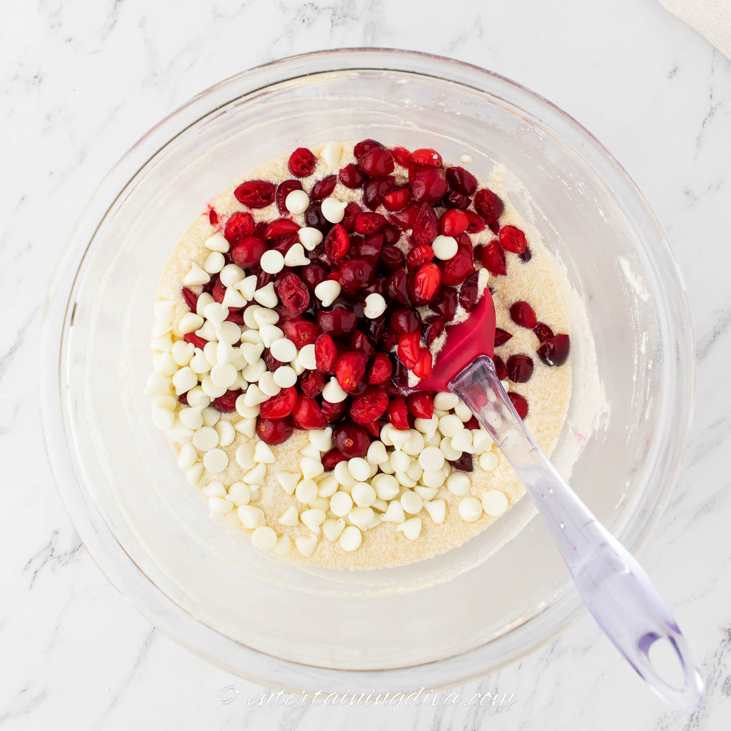 cranberries and white chocolate chips with cupcake mixture in a bowl