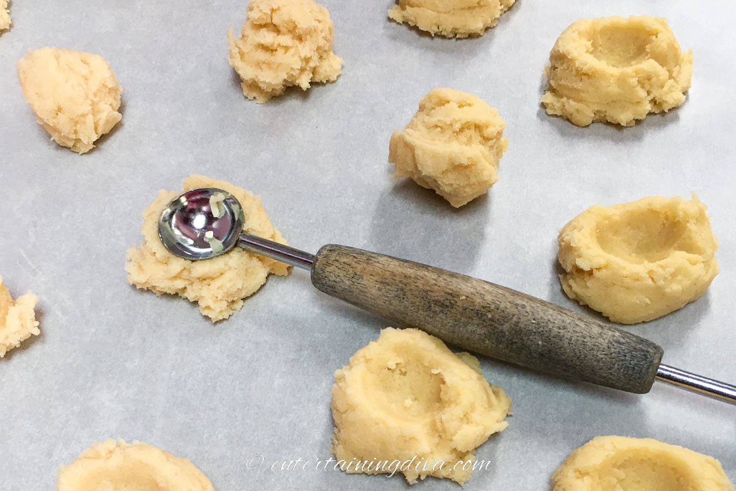 holes being made in the middle of the cookies with a melon baller