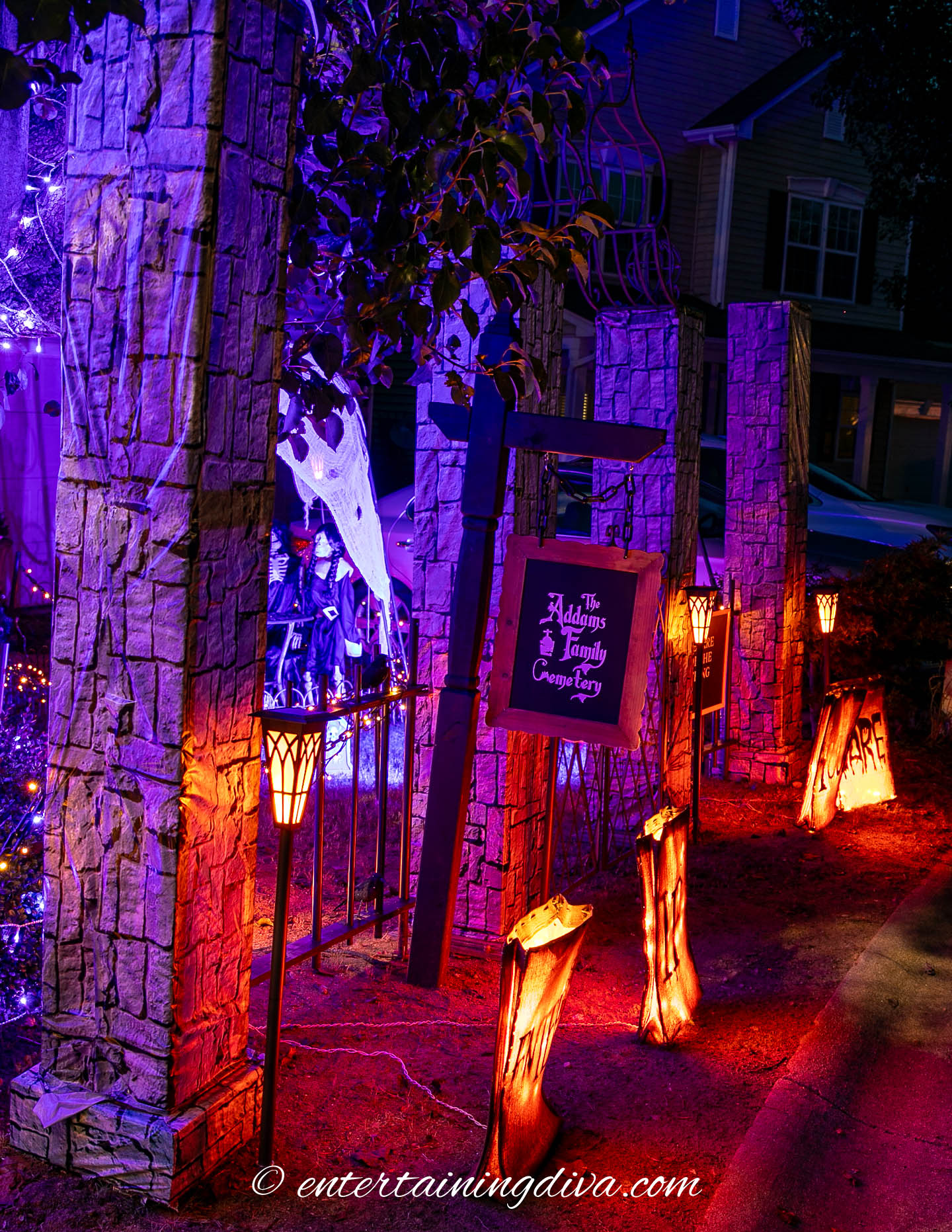 A Halloween front yard display with a sign that says "The Addams Family Cemetery"