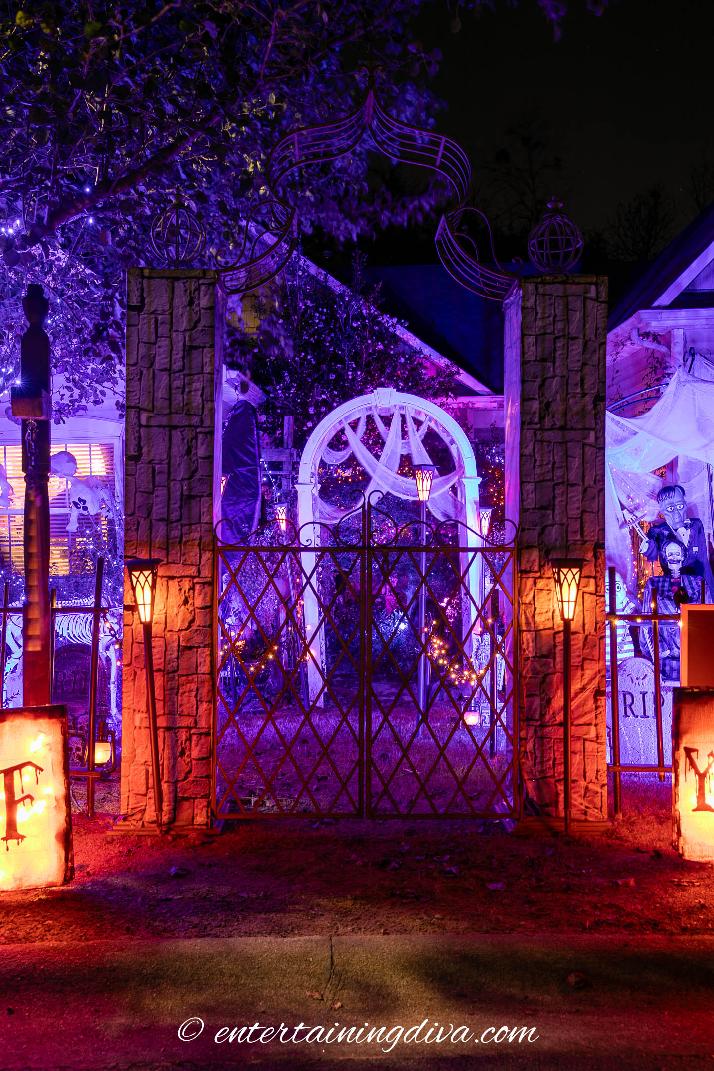 Orange lights in front of an Addams Family cemetery Halloween display
