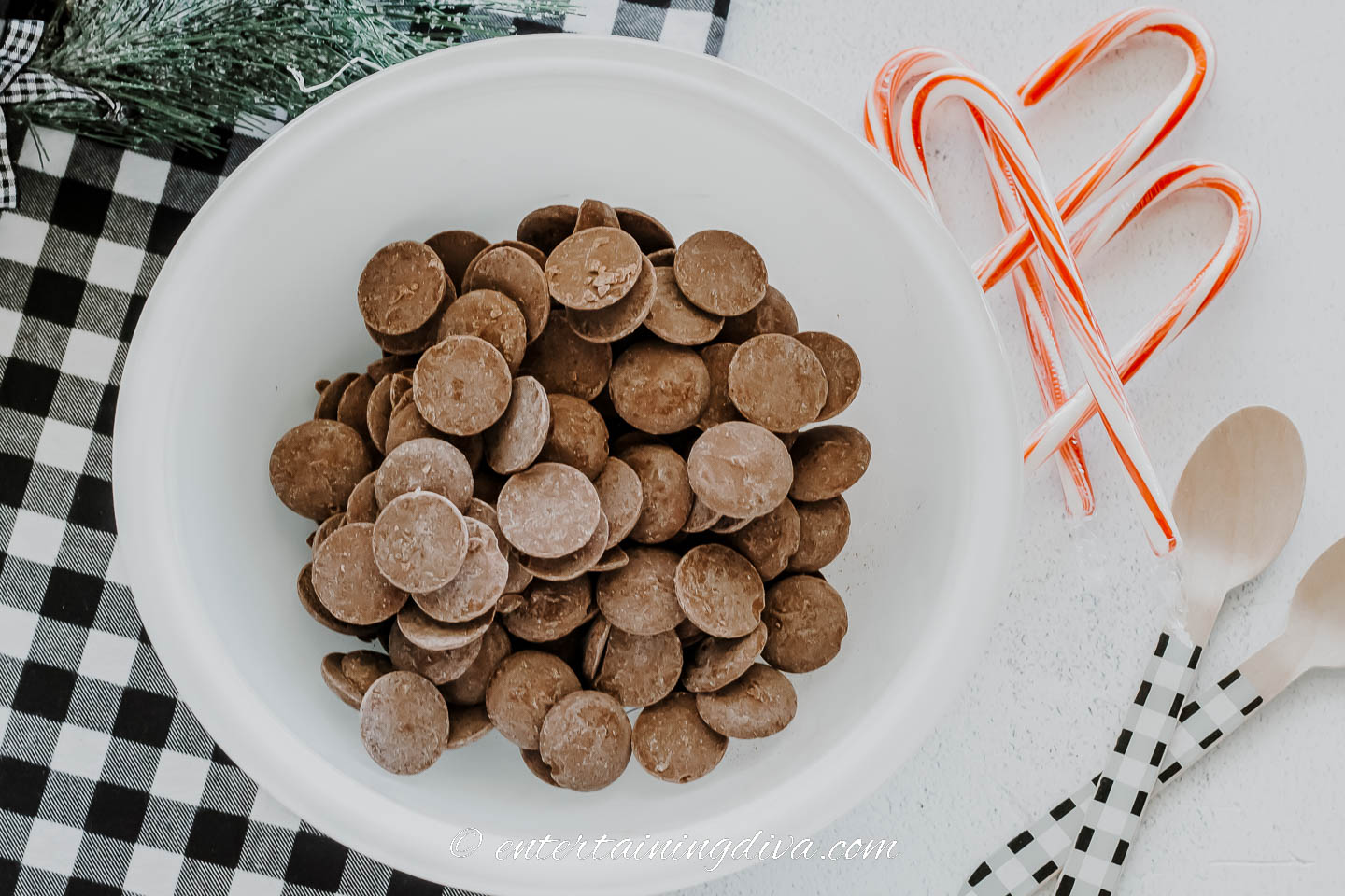 hot chocolate spoons ingredients and materials - A bowl of chocolate candies, candy canes and wooden stirring spoons