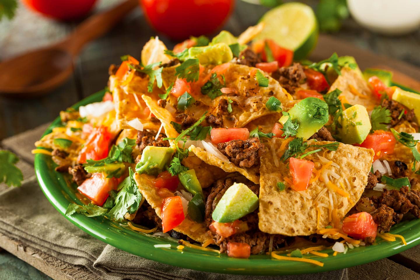 Nachos with ground beef, cheddar cheese, chopped avocado and tomatoes
