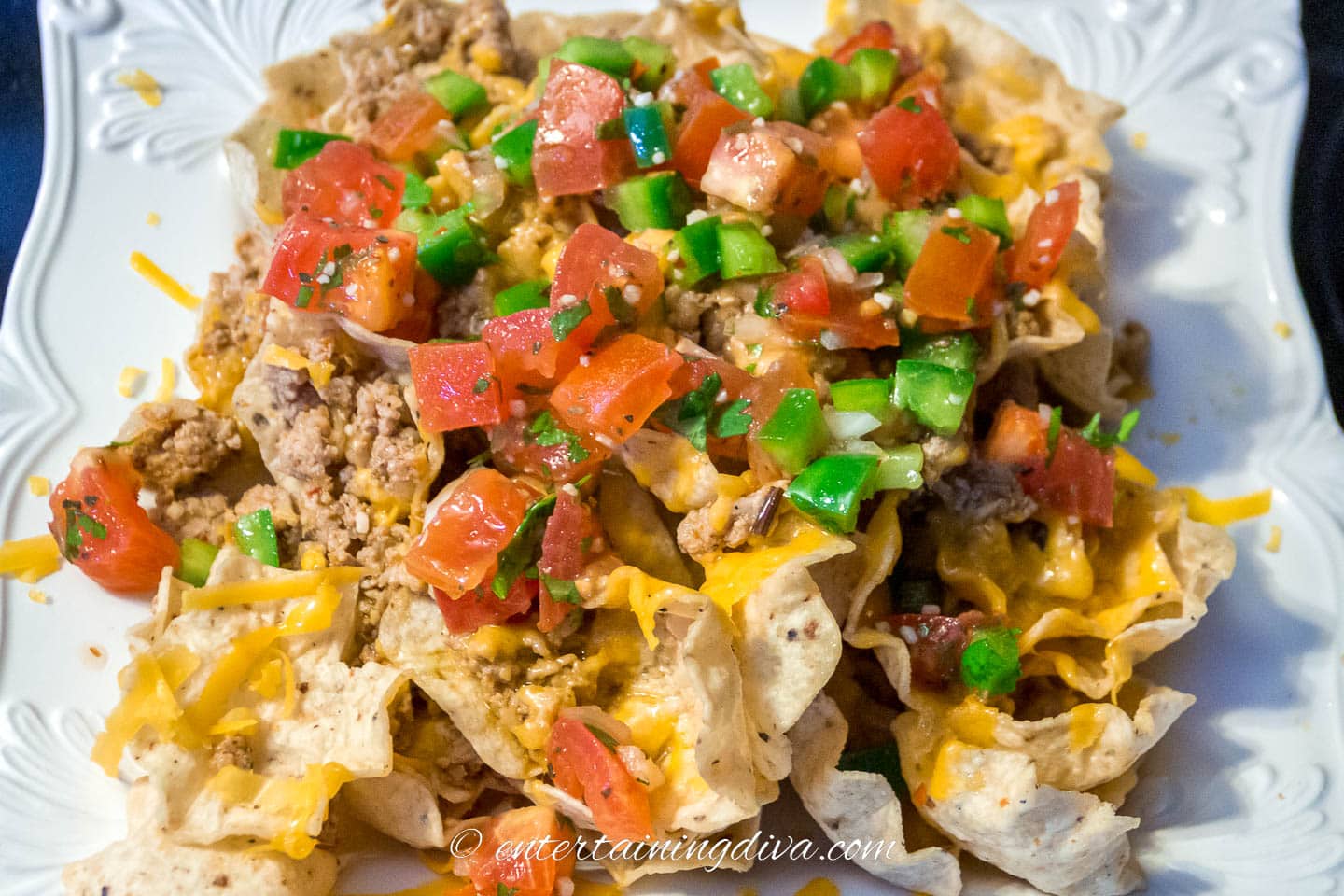 homemade nachos with ground beef, cheddar cheese, tomatoes, green peppers and pico de gallo as toppings