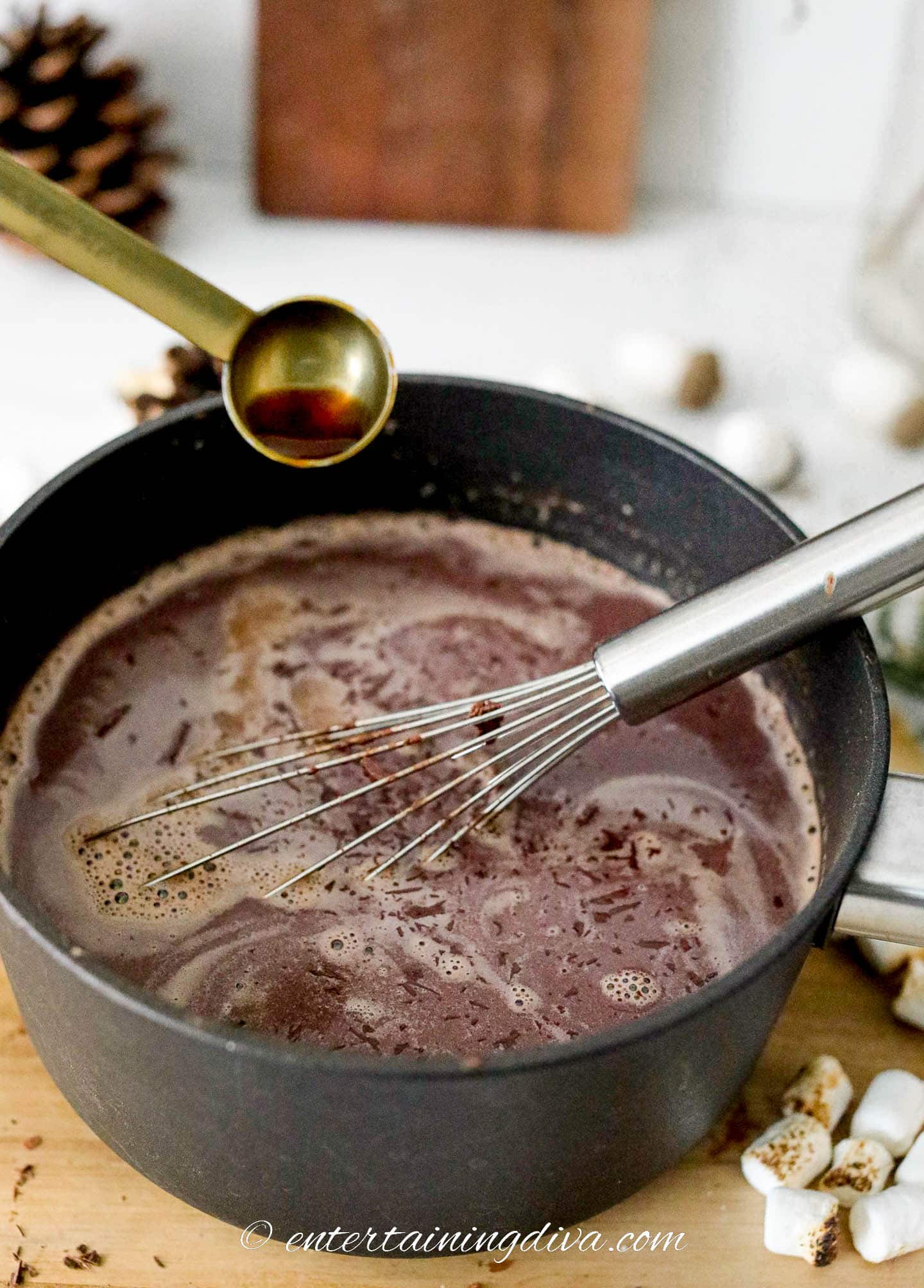Vanilla being added to hot chocolate in a pot