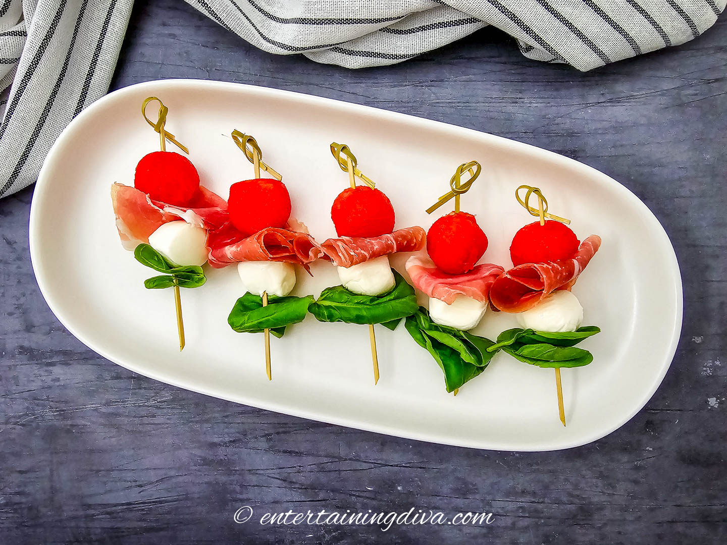 A tray of watermelon caprese skewers on a dark background