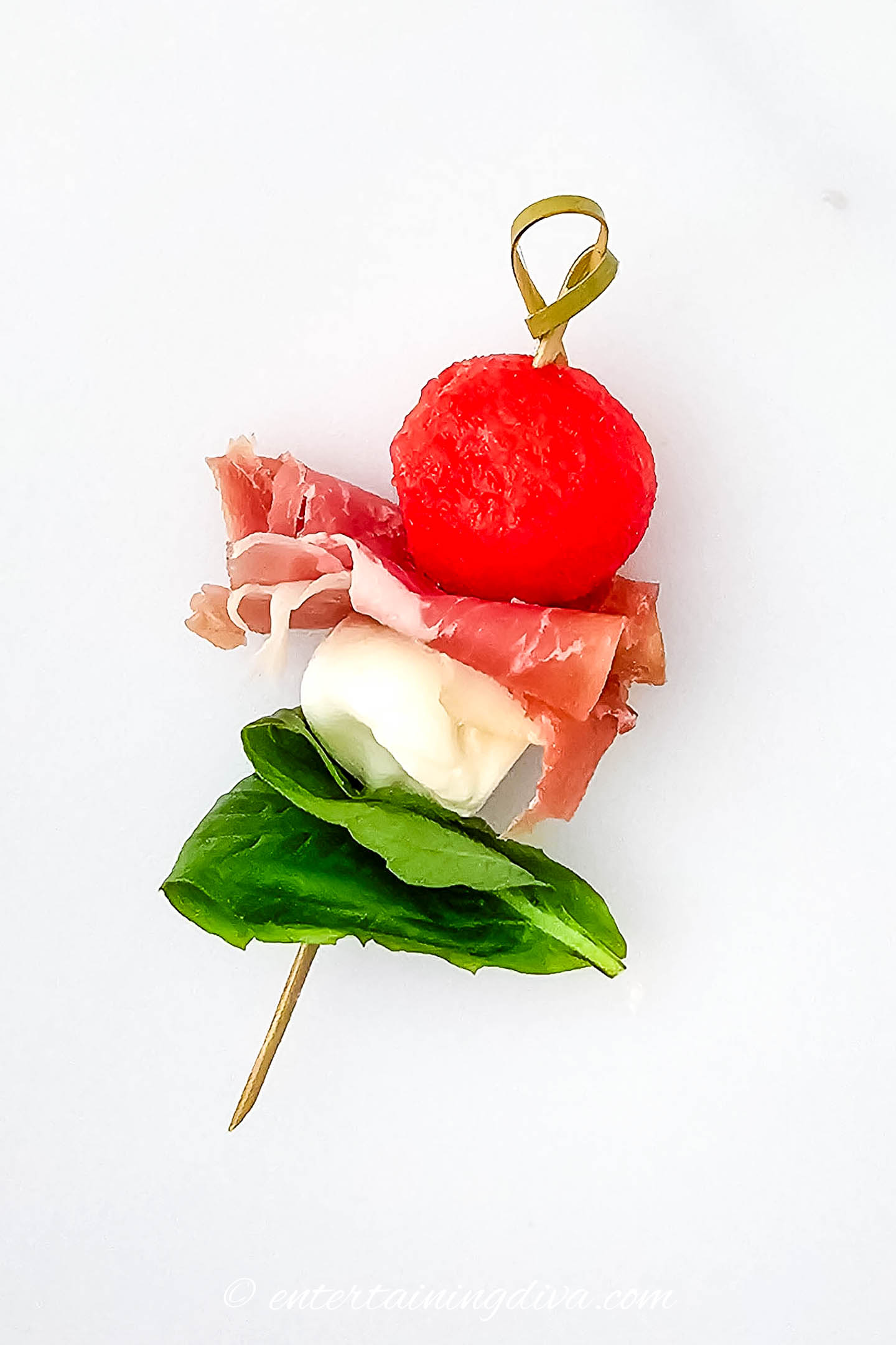 A watermelon caprese skewer on a white background