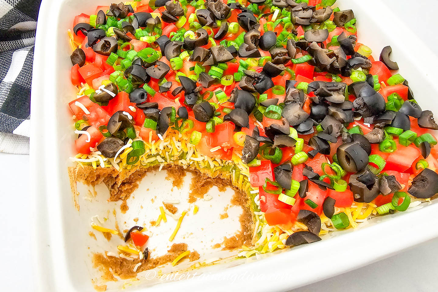7-layer dip with part of it eaten in a white dish