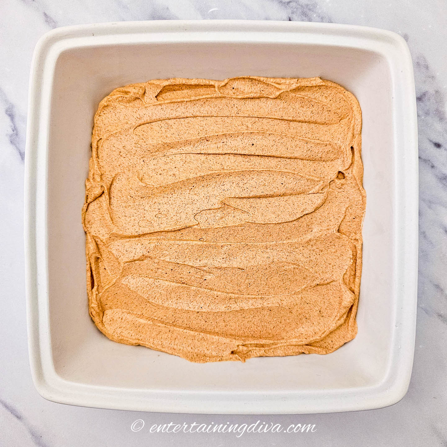 sour cream mix layered on top of refried beans in a 7-layer dip