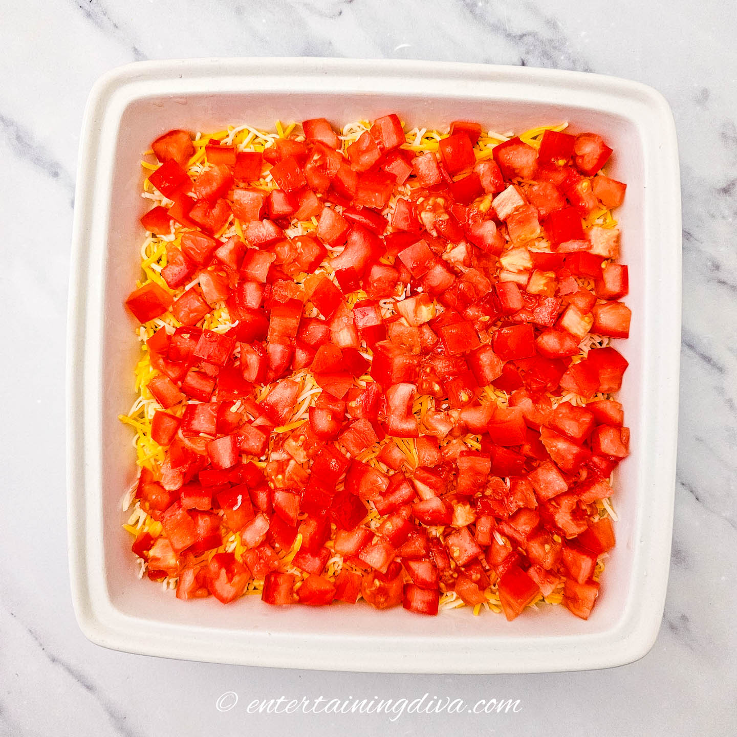 a layer of chopped tomatoes over the layer of cheese in a 7-layer dip
