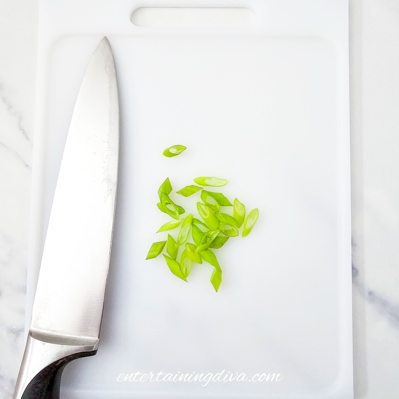 Sliced green onions on a cutting board with a knife