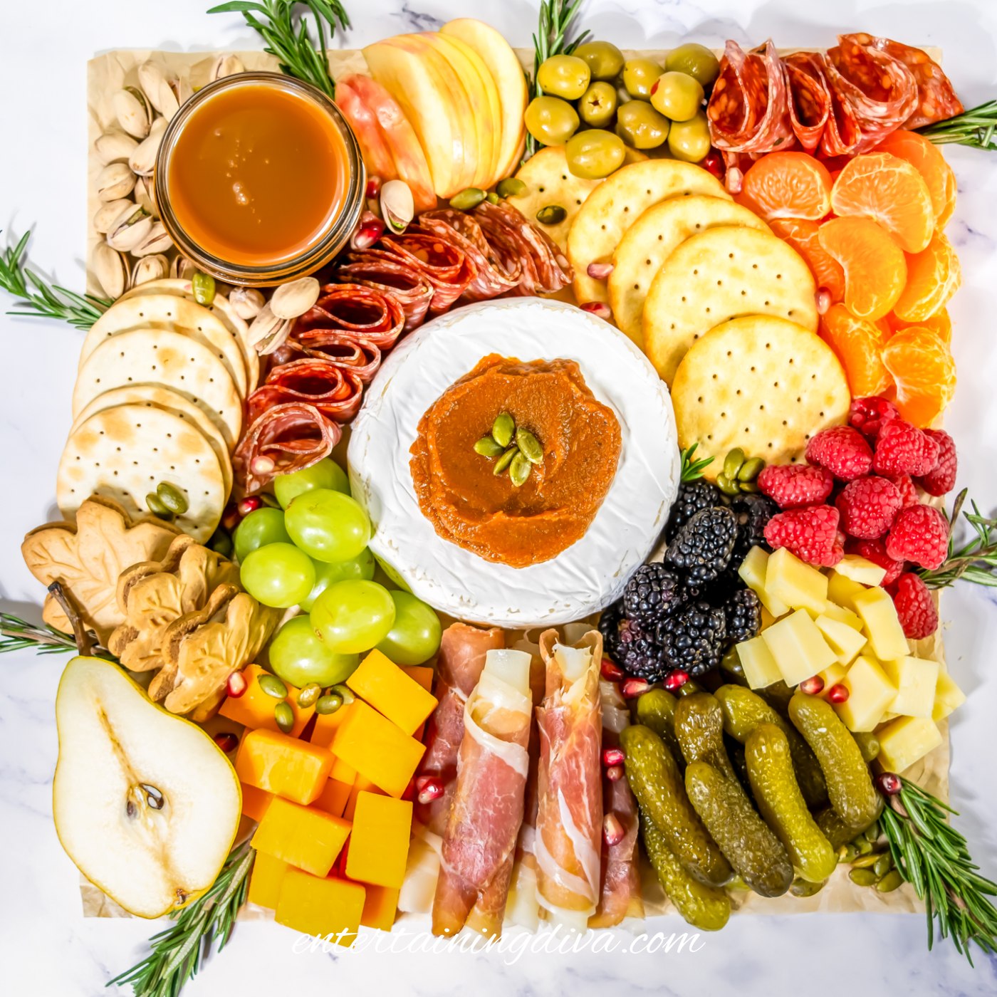 A fall charcuterie board garnished with rosemary and pomegranate seeds