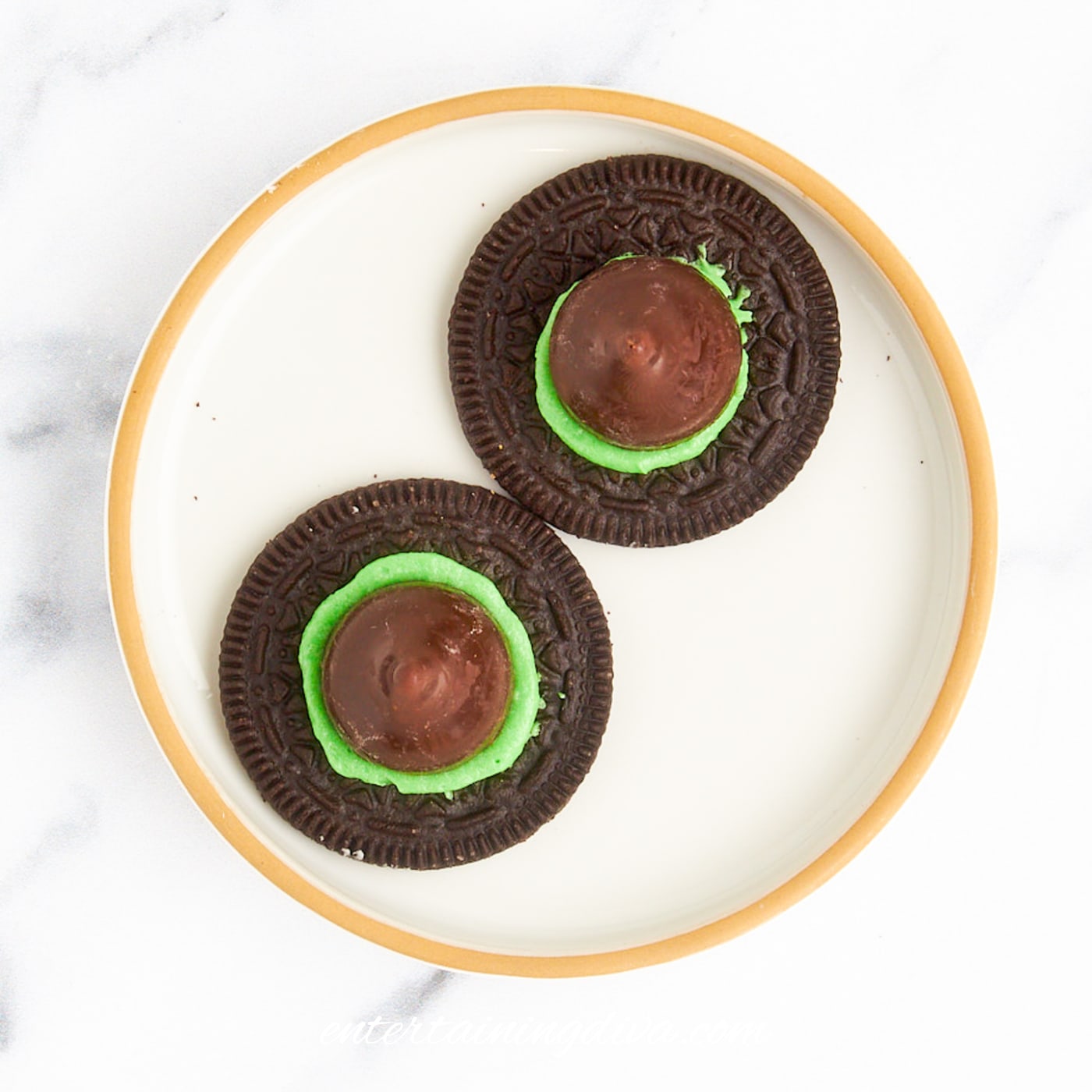 A witch hat made from a hershey's kiss on green frosting on top of half an Oreo cookie