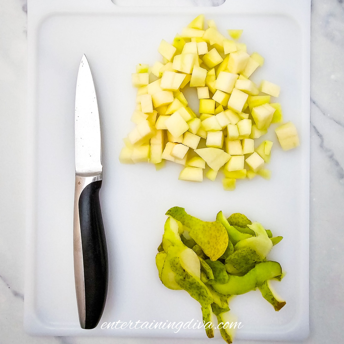 Diced pear on a cutting board with a paring knife