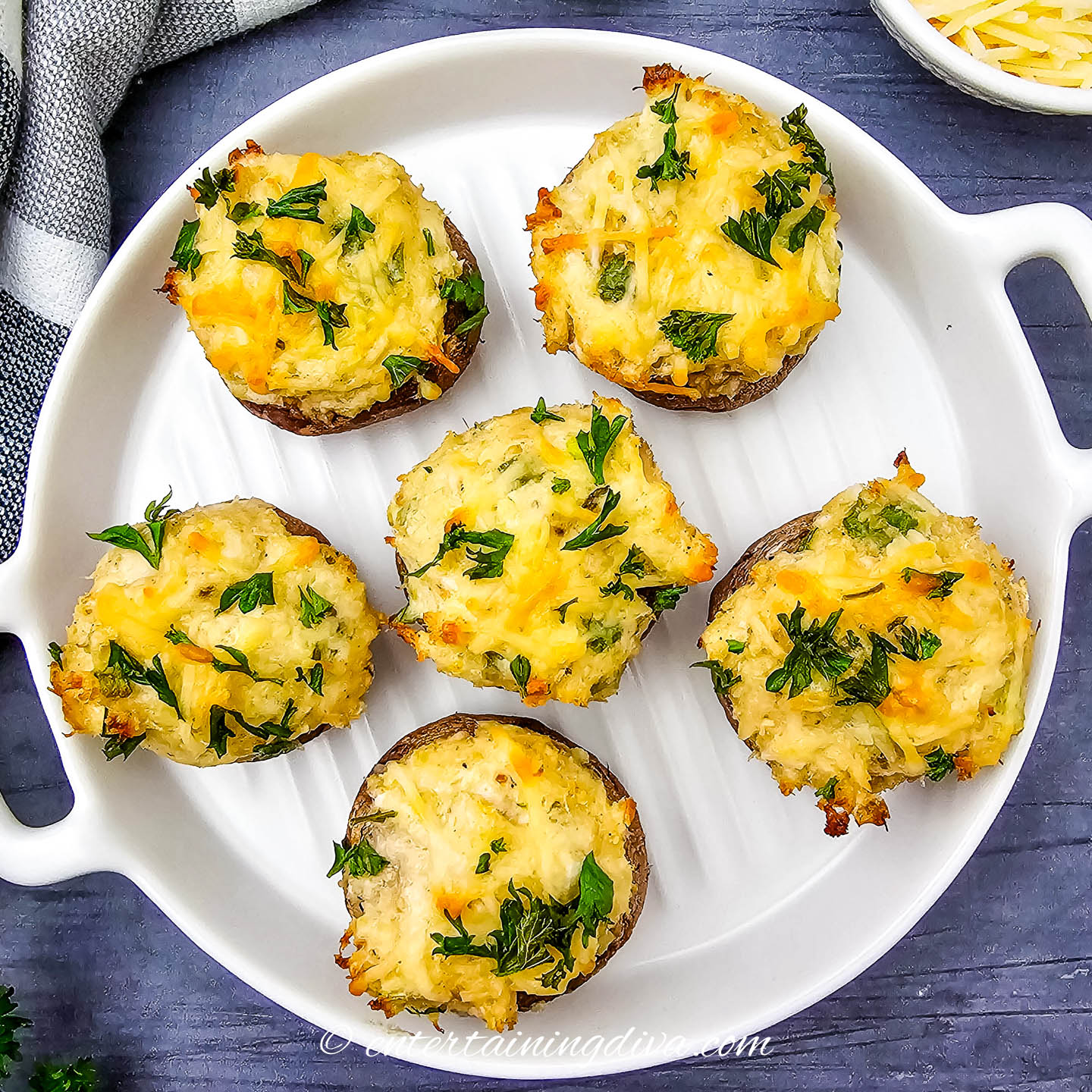 Baked crab-stuffed mushrooms in a white baking pan on a dark surfance
