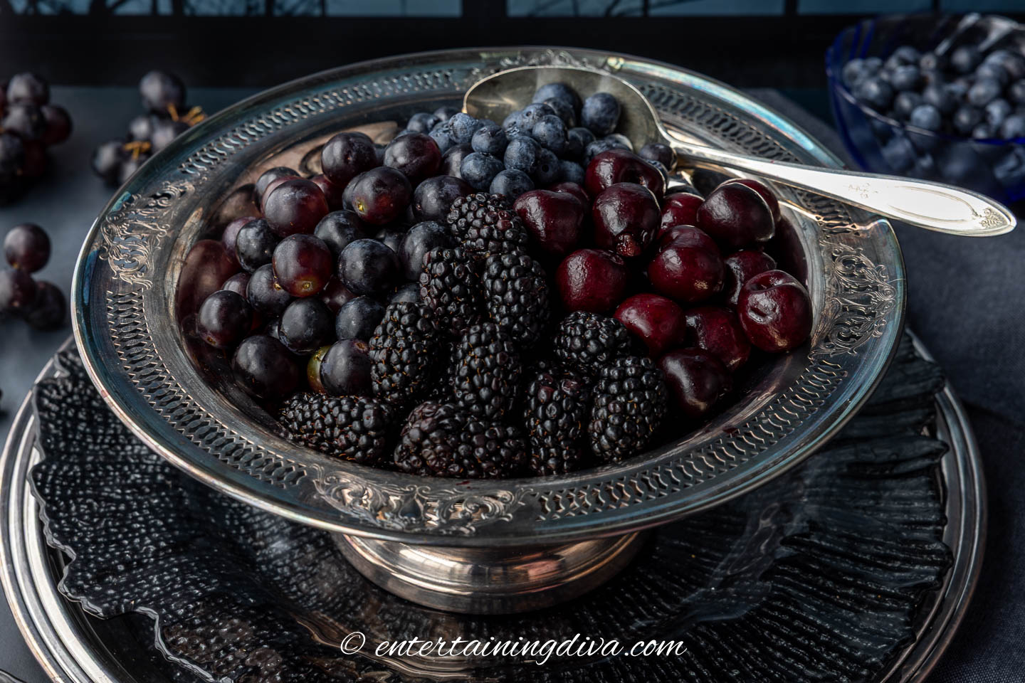 close up of dark Halloween fruit salad in a silver serving bowl