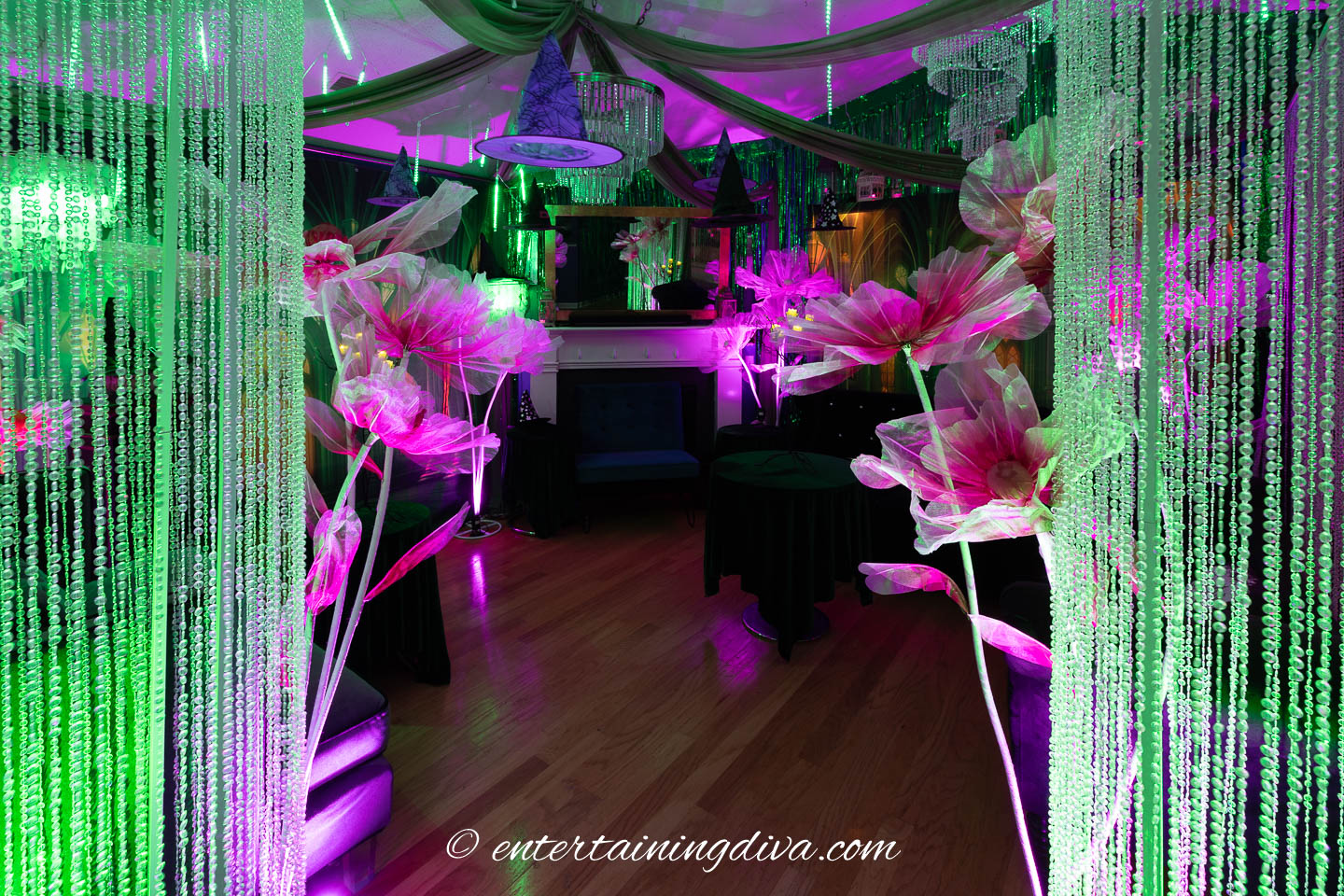 Green and pink uplights used to light crystal columns and large pink poppies at a Wicked Halloween party