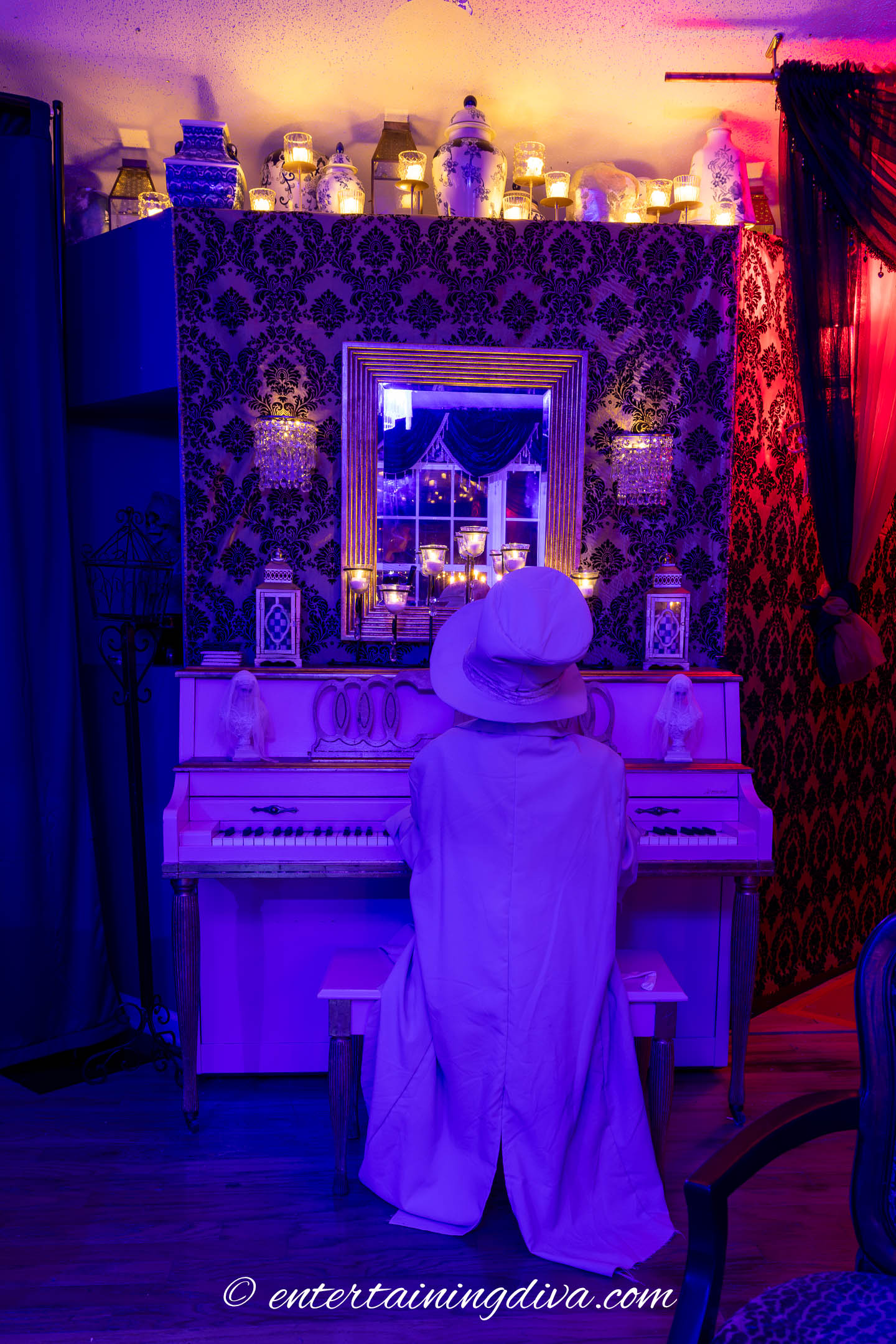 Flameless candles on a piano and the top of wall with a skeleton playing the piano in a Halloween haunted house